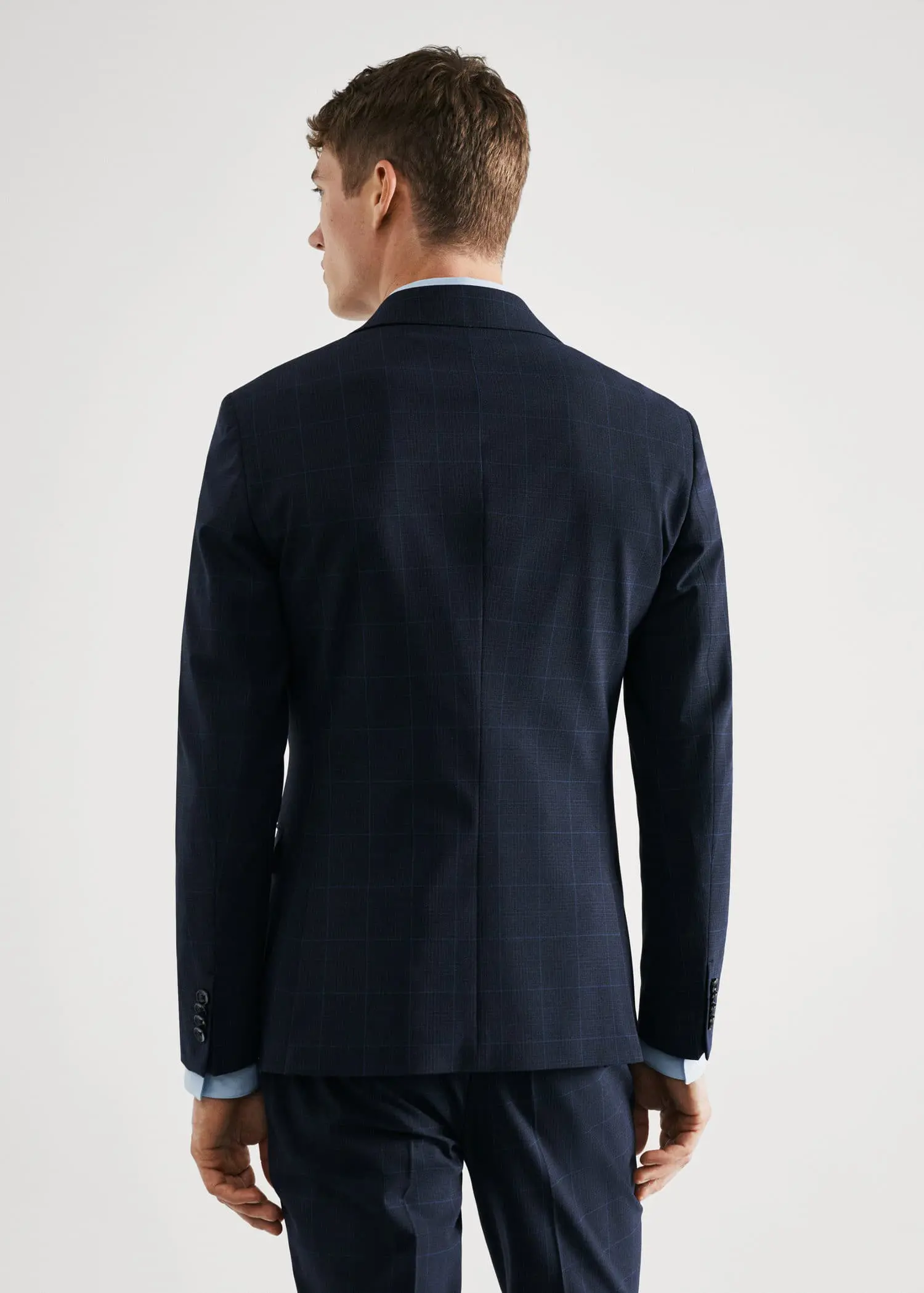 Mango Super slim-fit check suit blazer. a man wearing a suit standing in front of a white wall. 
