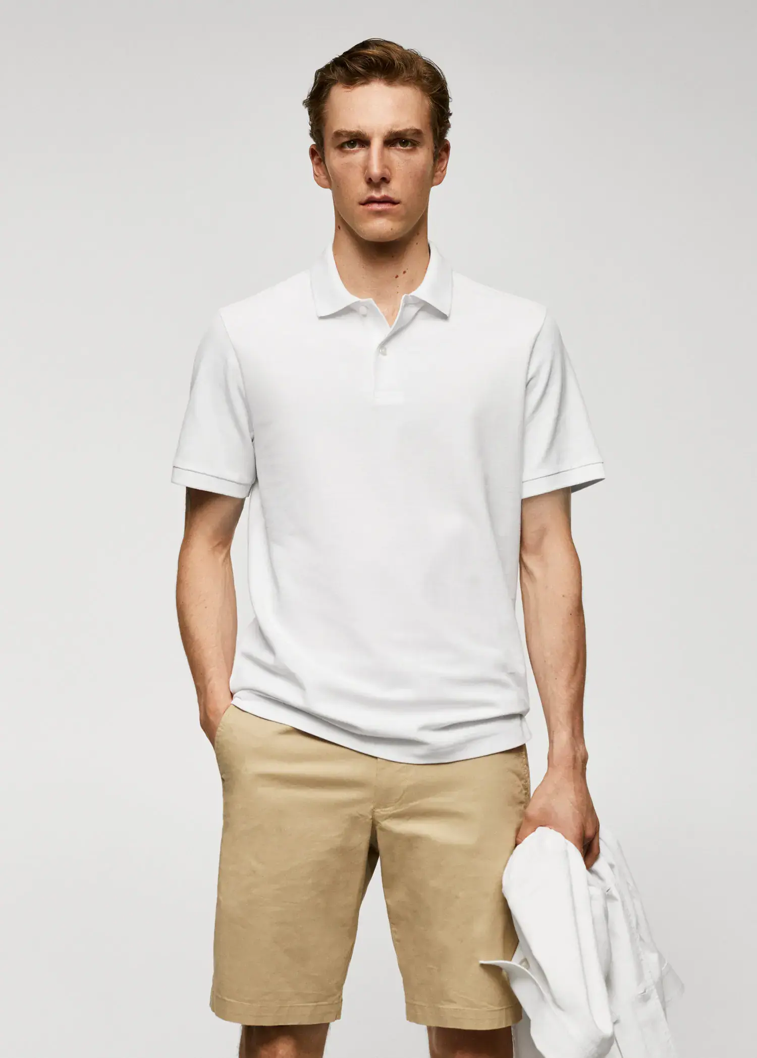 Mango 100% cotton pique polo shirt. a man in a white polo shirt holding a hat. 