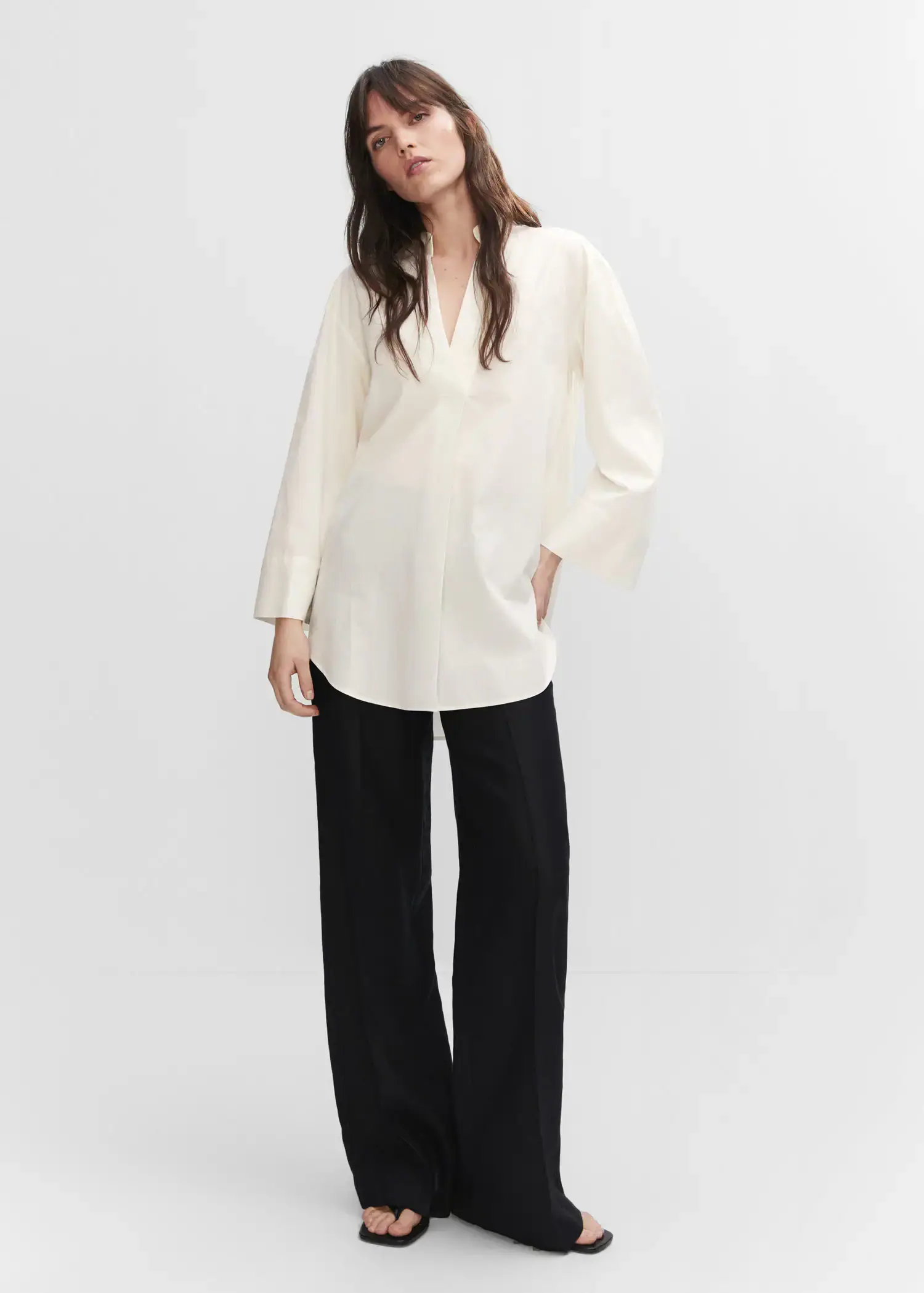 Mango Oversized V-neck blouse. a woman wearing a white shirt and black pants. 