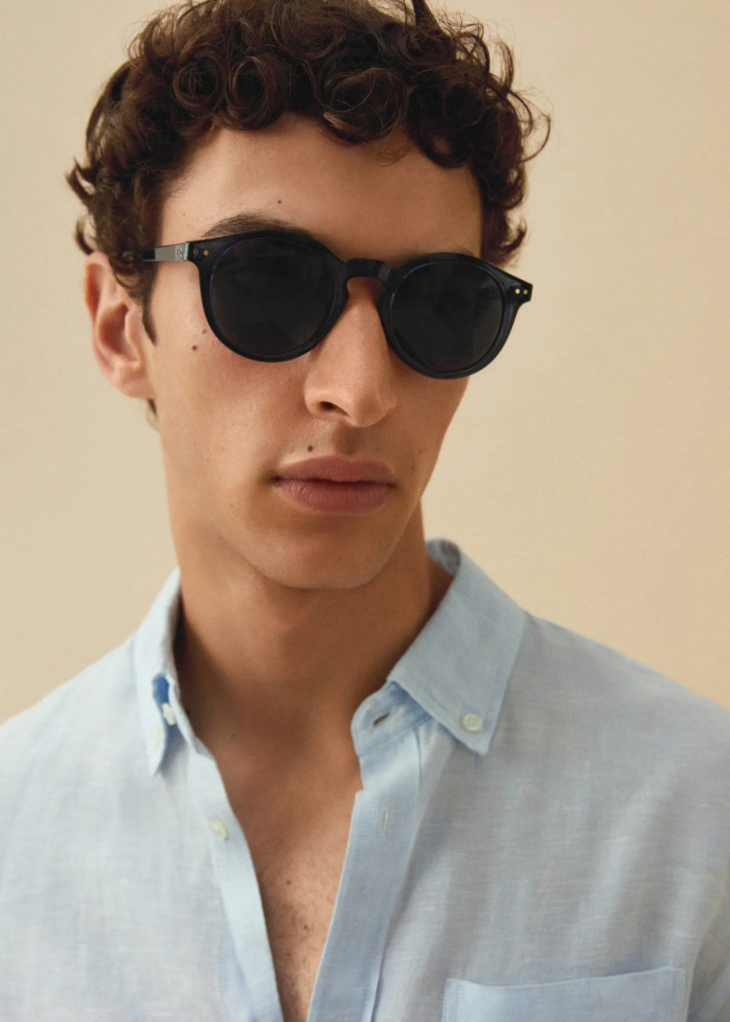 Mango Polarised sunglasses. a young man wearing sunglasses and a blue shirt. 