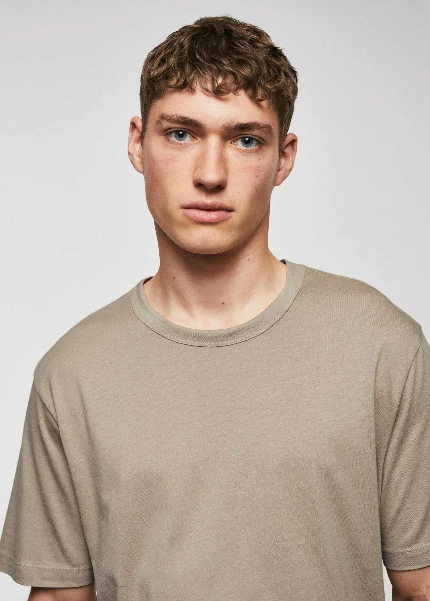 Mango Basic mercerised lightweight shirt. a young man in a tan shirt is posing for a picture. 