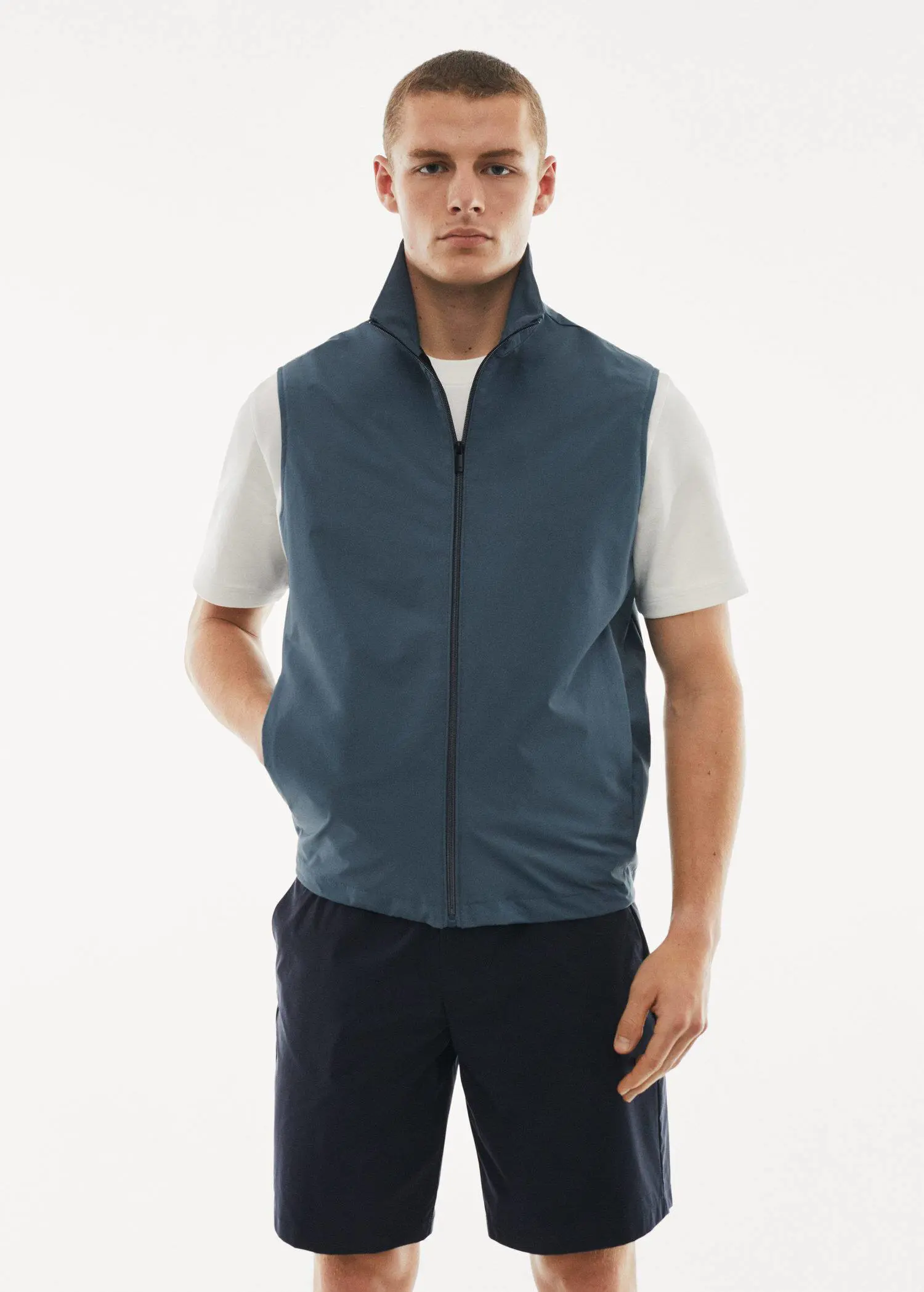 Mango Water-repellent technical vest. a man wearing a vest standing in front of a white wall. 