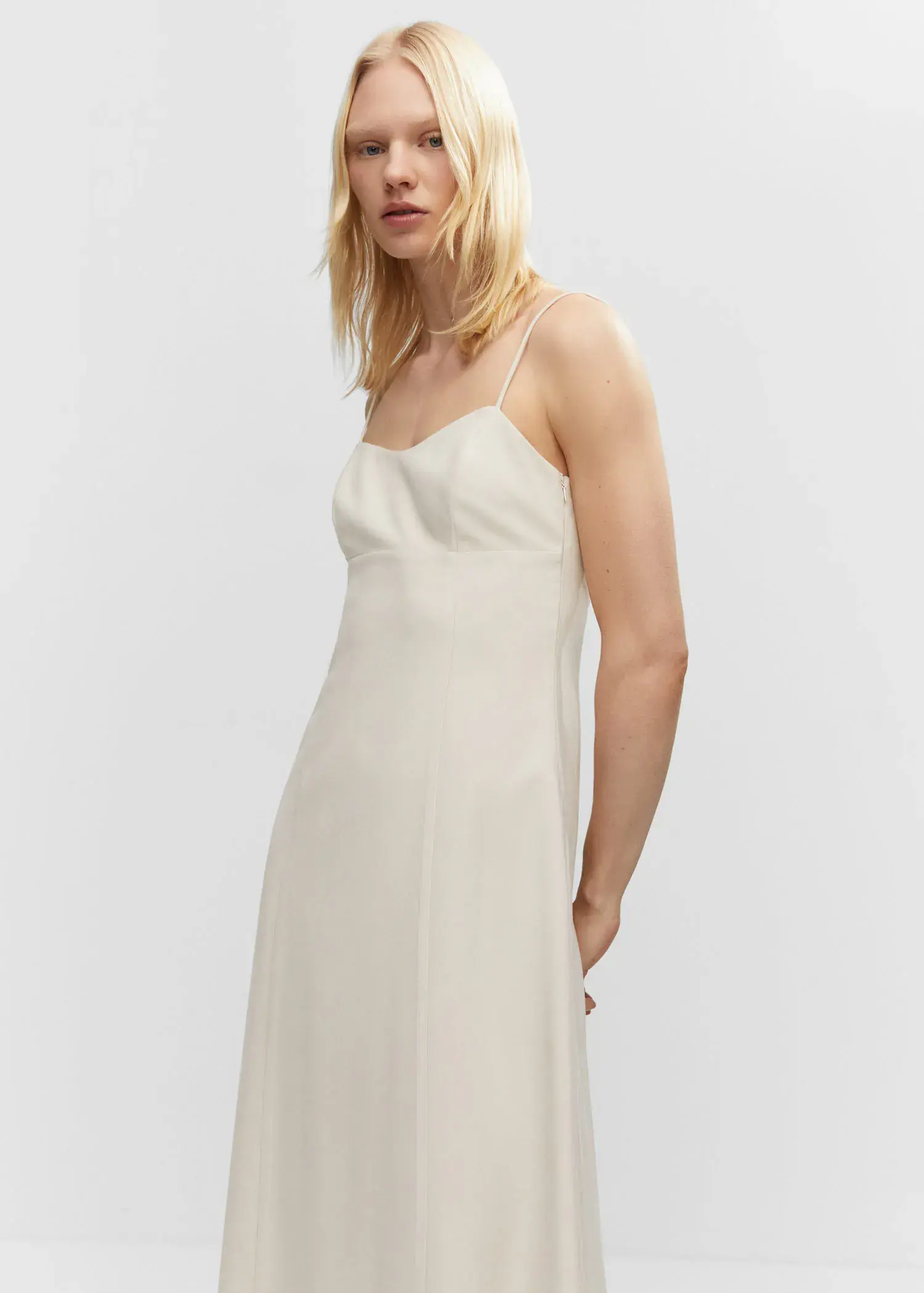 Mango Low-cut midi-dress. a woman wearing a white dress standing in front of a white wall. 