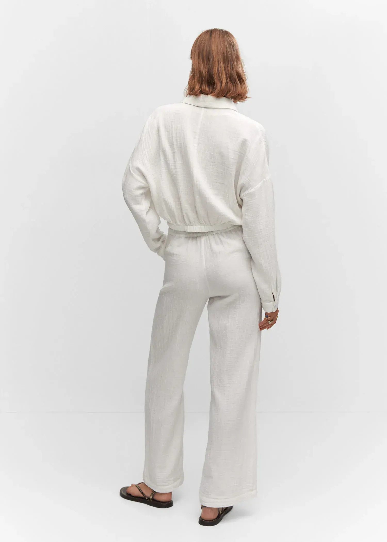 Mango Bow textured pants. a person wearing a white outfit standing in front of a wall. 