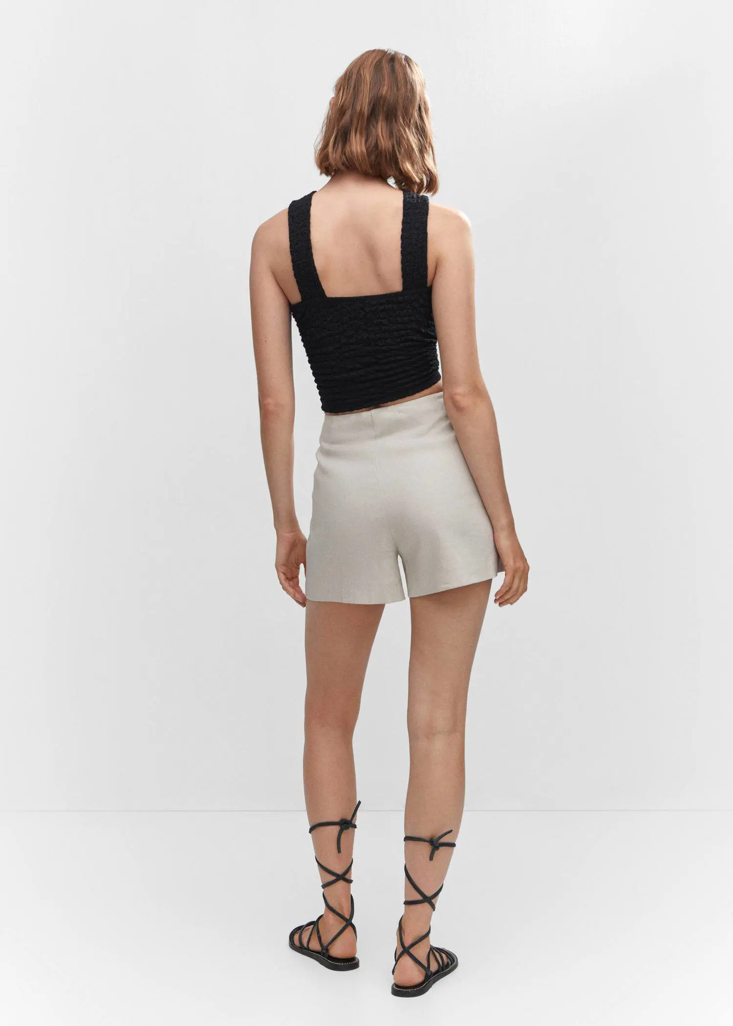 Mango Textured top with ring detail. a woman wearing a black top and white shorts. 