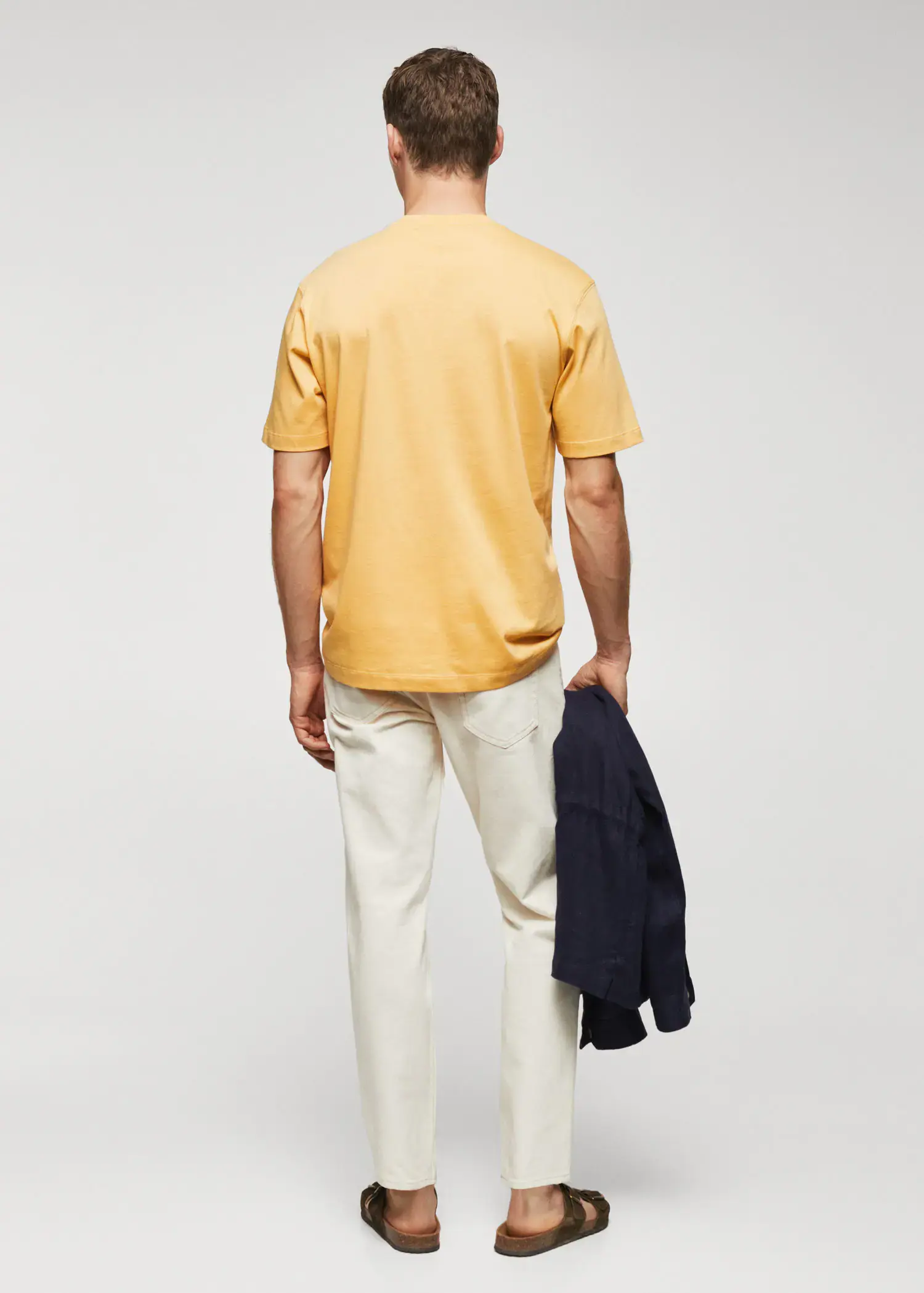 Mango Adriana Eskenazi x Mango t-shirt. a man in a yellow shirt holding a jacket. 