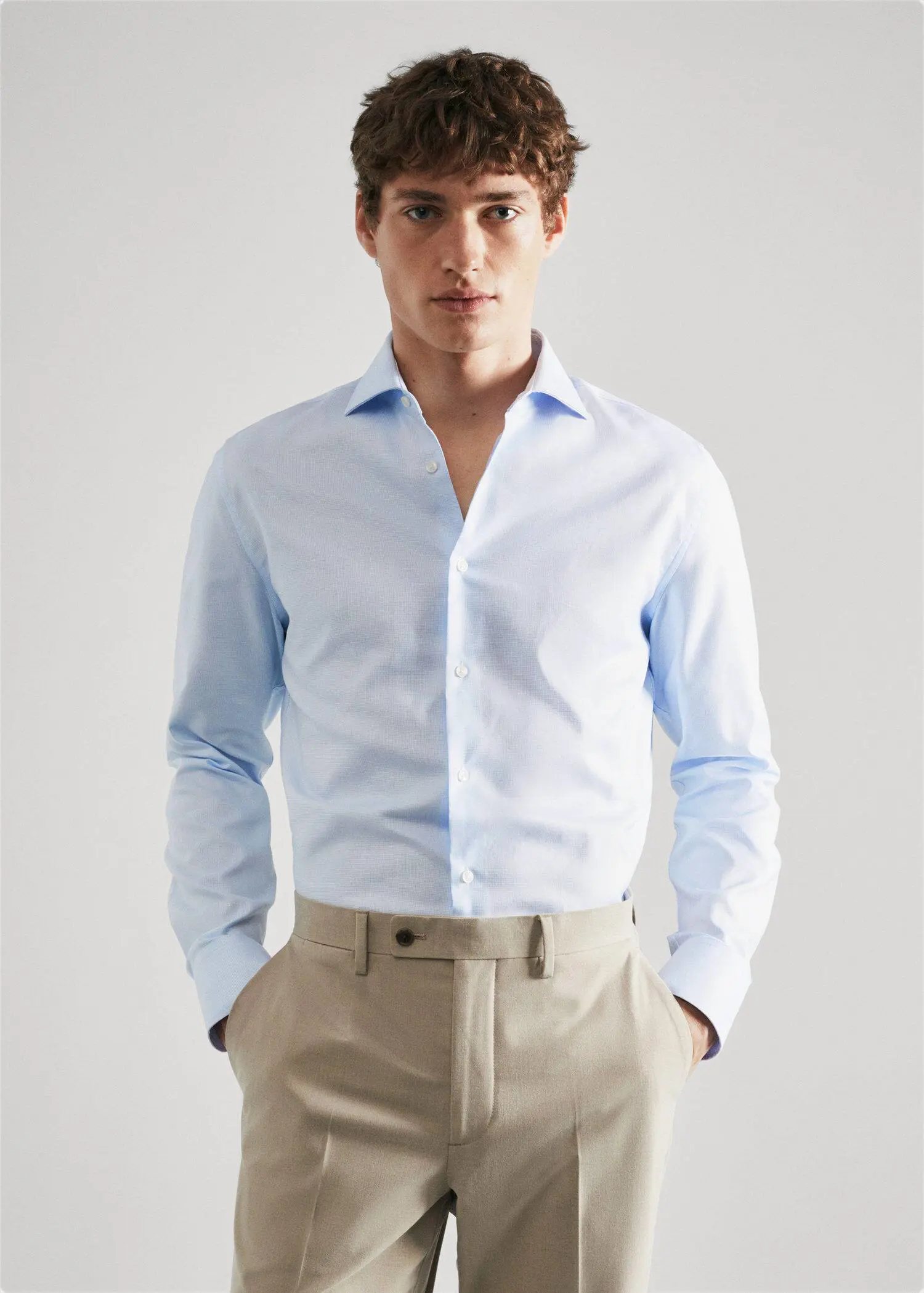 Mango Slim fit structured suit shirt. a man wearing a light blue dress shirt and beige pants. 