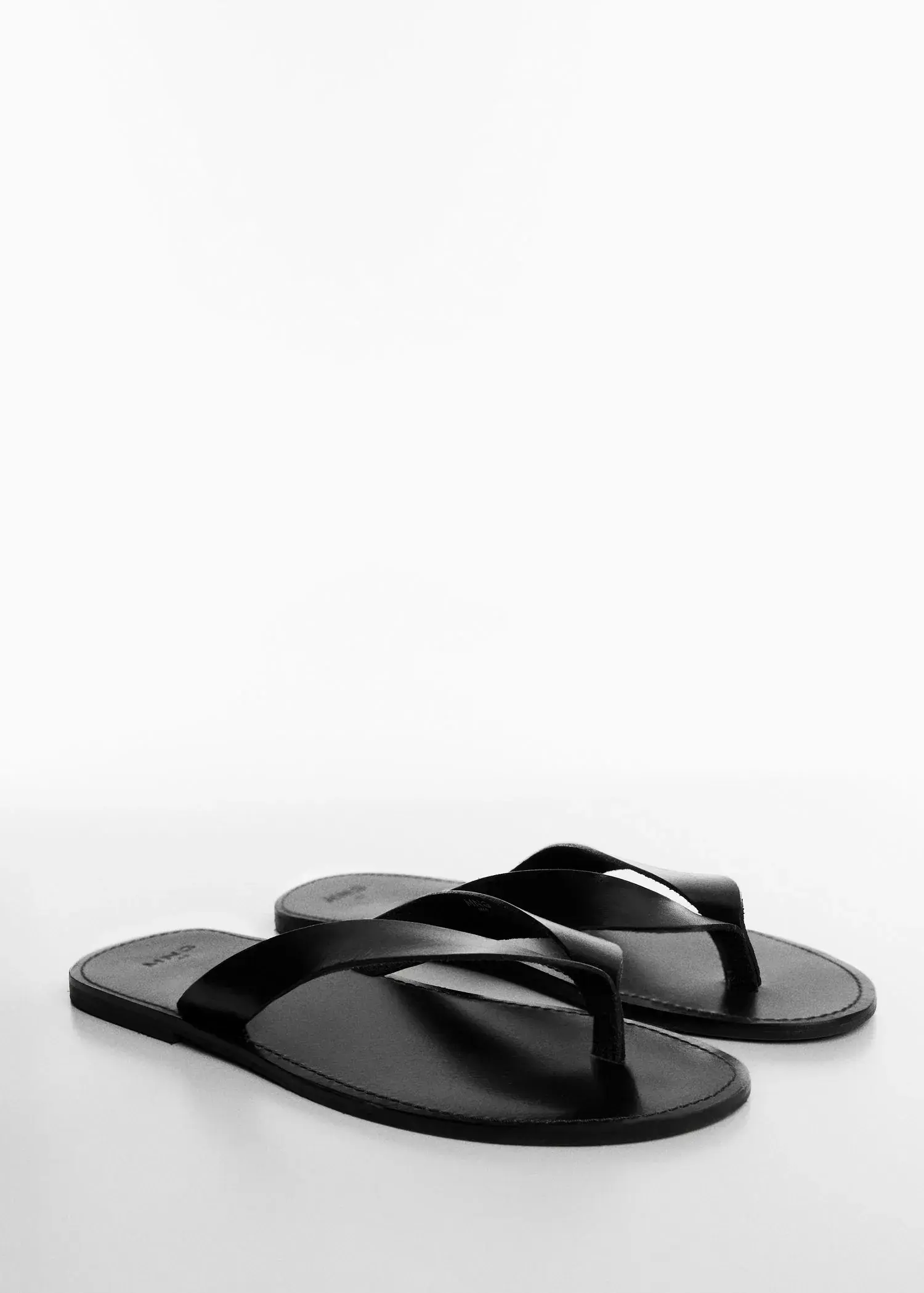 Mango Leather straps sandals. a pair of black flip flops sitting on top of a table. 