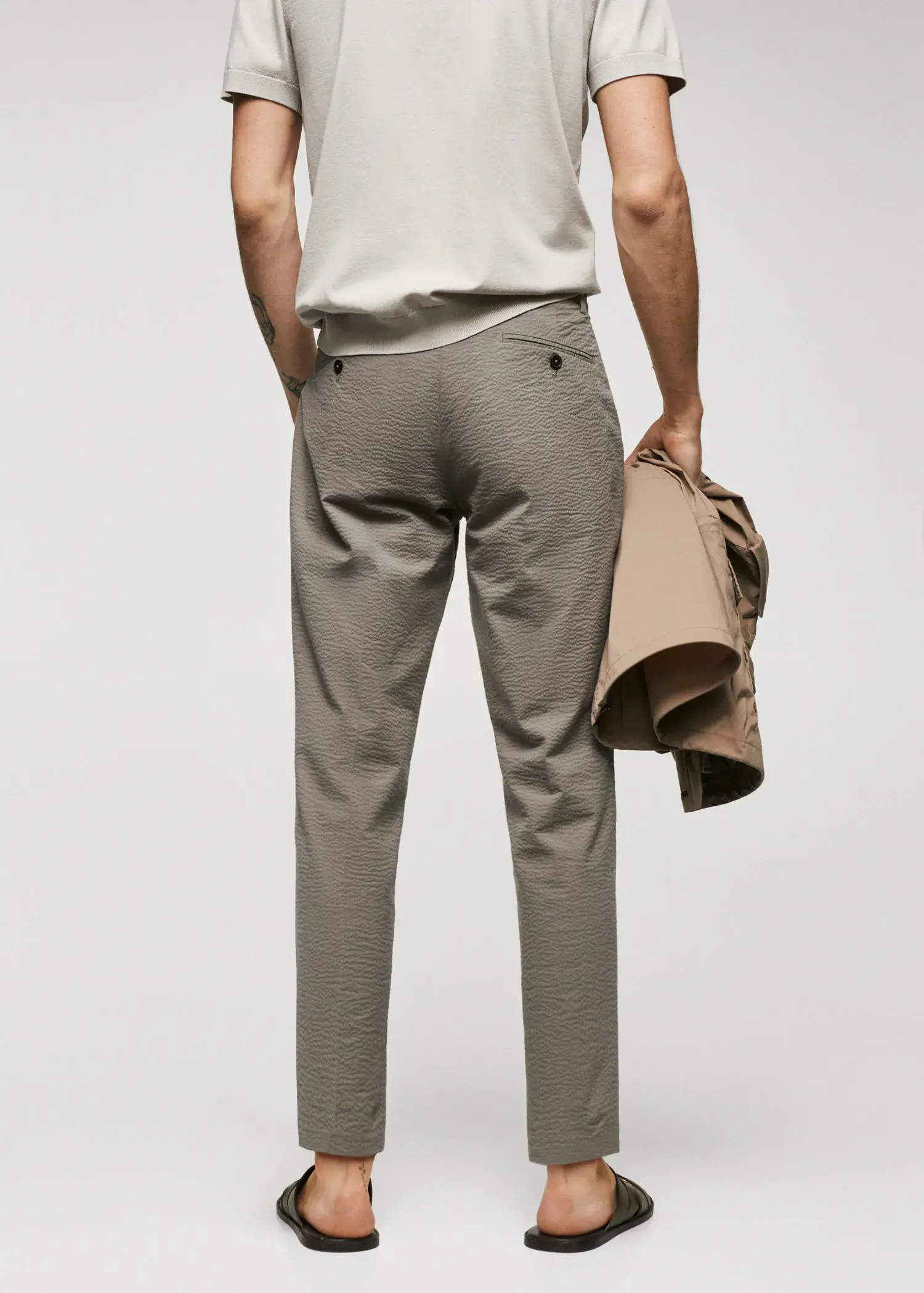 Mango Slim-fit seersucker stretch pants. a man holding a bag in his right hand. 