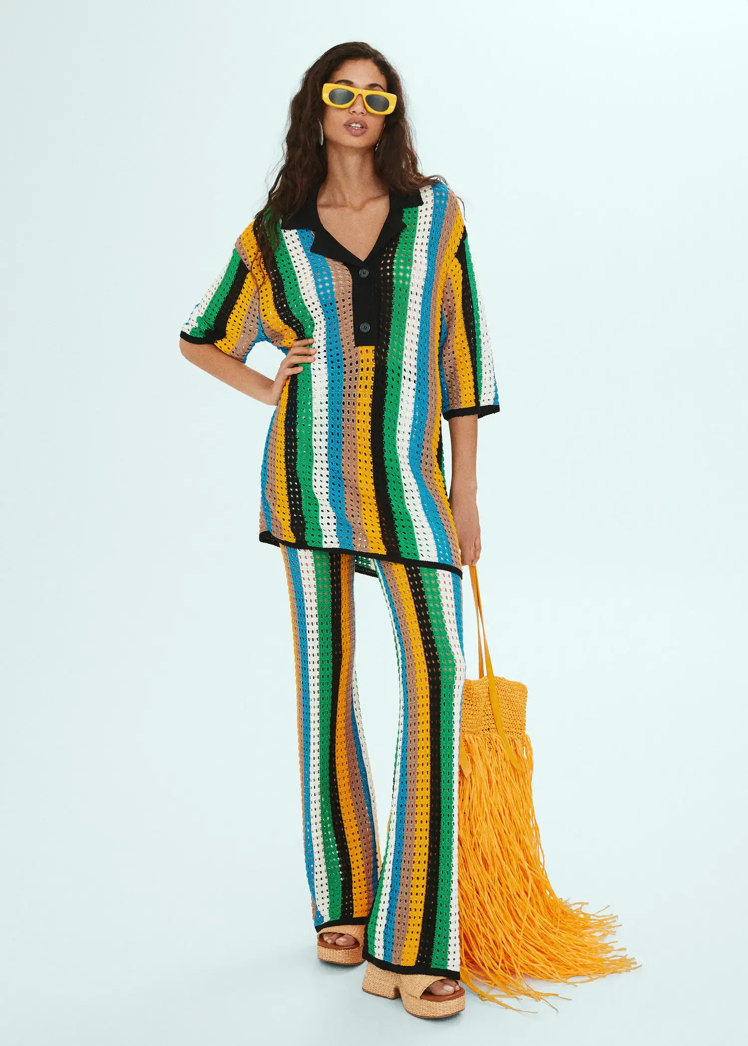 Mango Oversized openwork knitted polo shirt. a woman in a colorful outfit holding a yellow bag. 