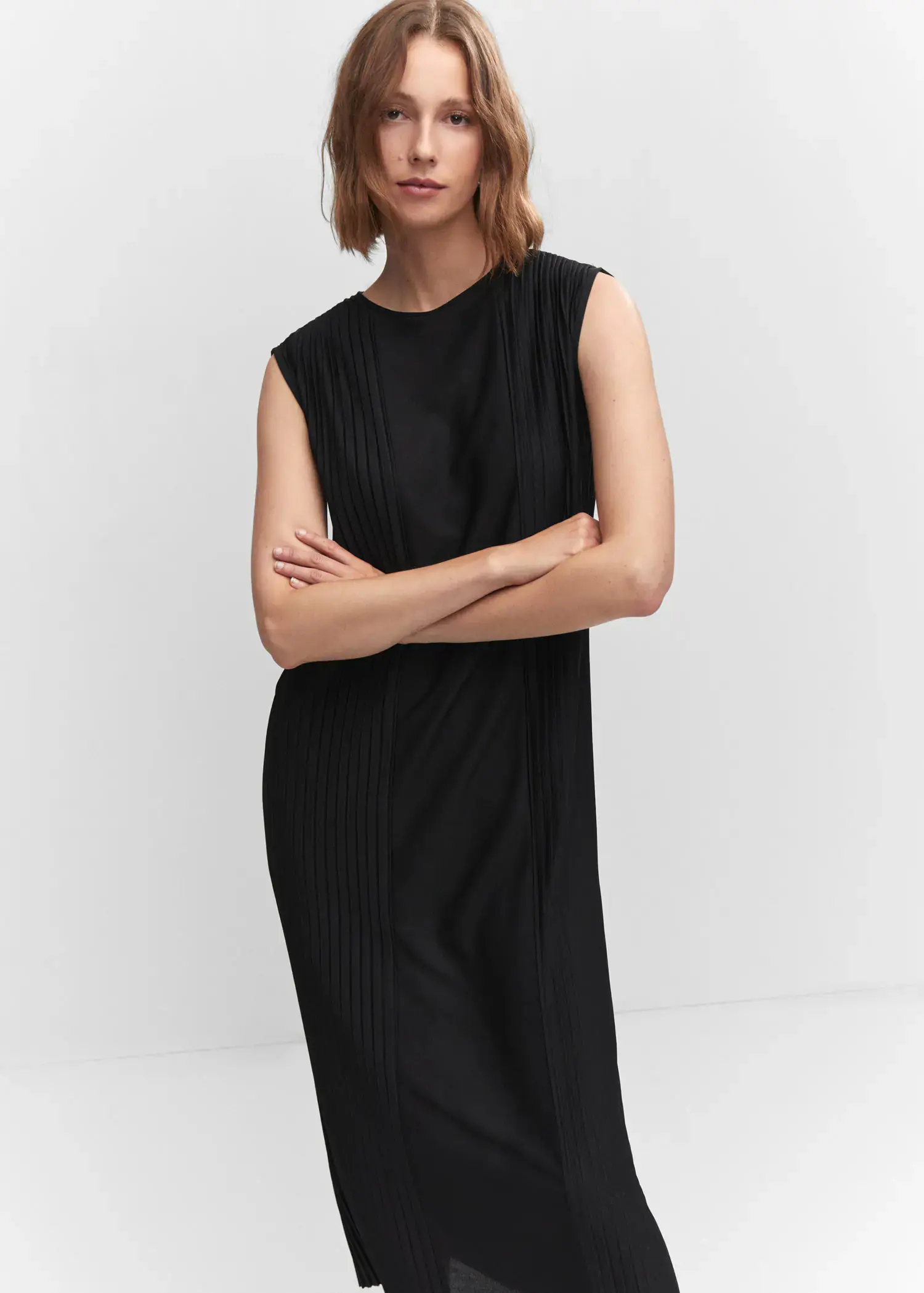 Mango Pleated detail dress. a woman wearing a black dress standing with her arms crossed. 