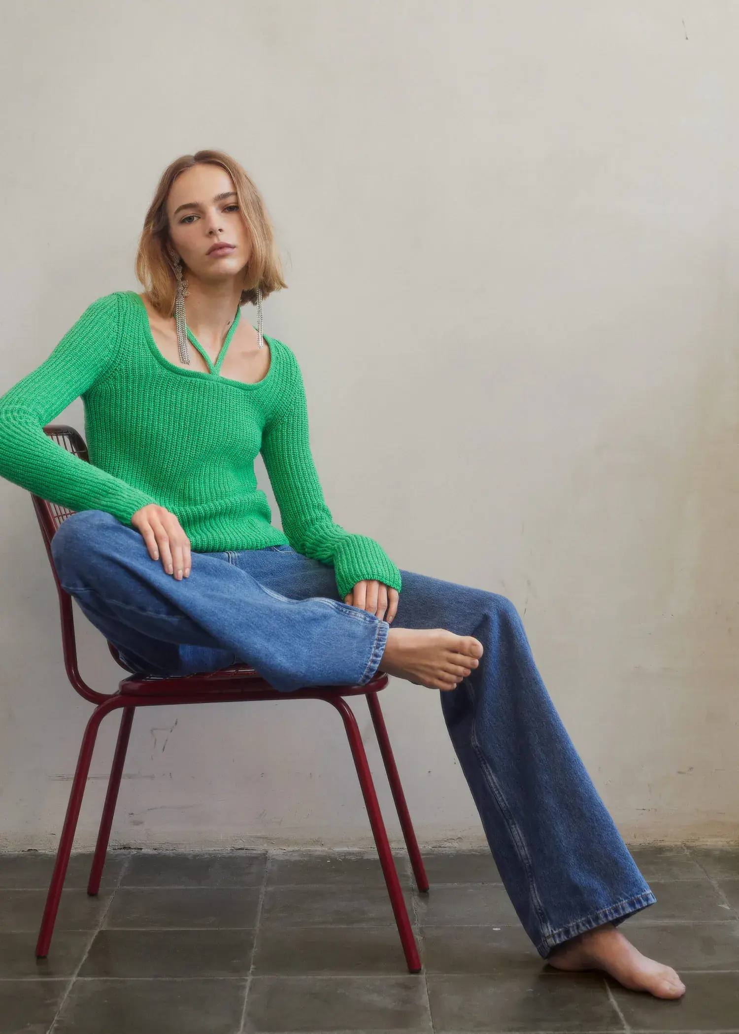 Mango Bow collar sweater. a woman sitting on a red chair wearing a green sweater. 