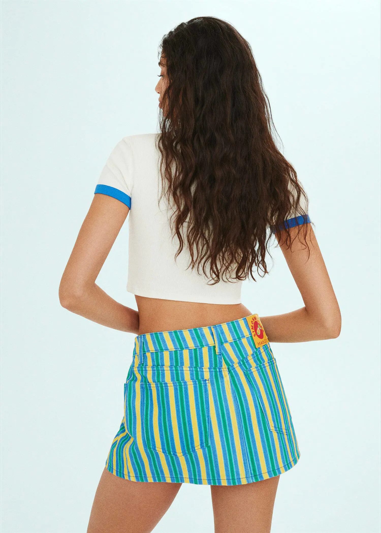 Mango Multi-colored striped denim mini-skirt. a woman in a white crop top and a blue and white striped skirt. 