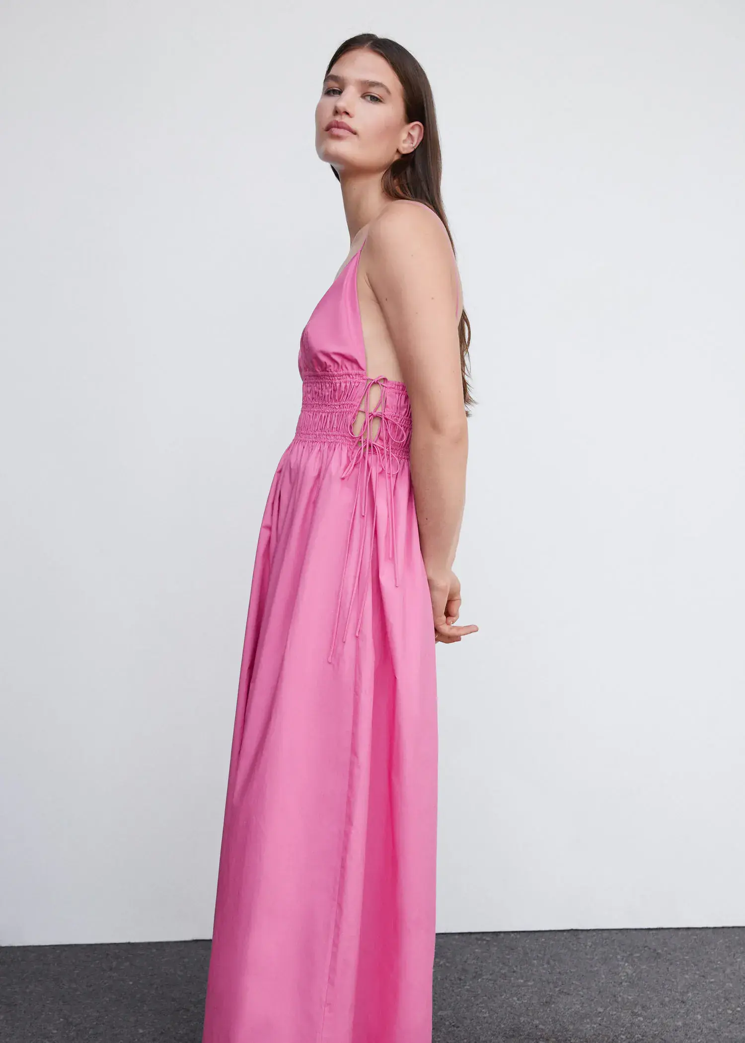 Mango Cotton dress with side ties. a woman wearing a pink dress standing next to a white wall. 