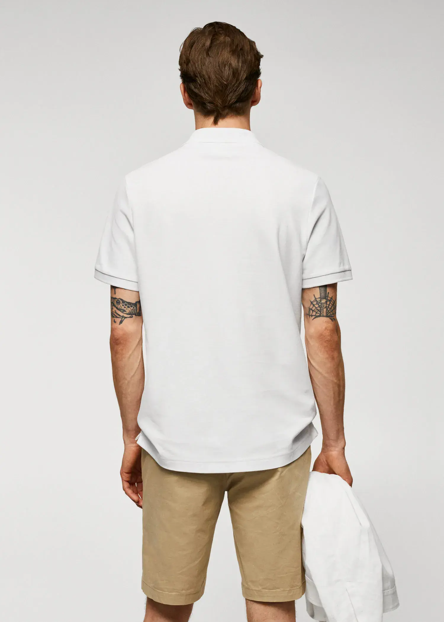 Mango 100% cotton pique polo shirt. a man wearing a white polo shirt and tan pants. 