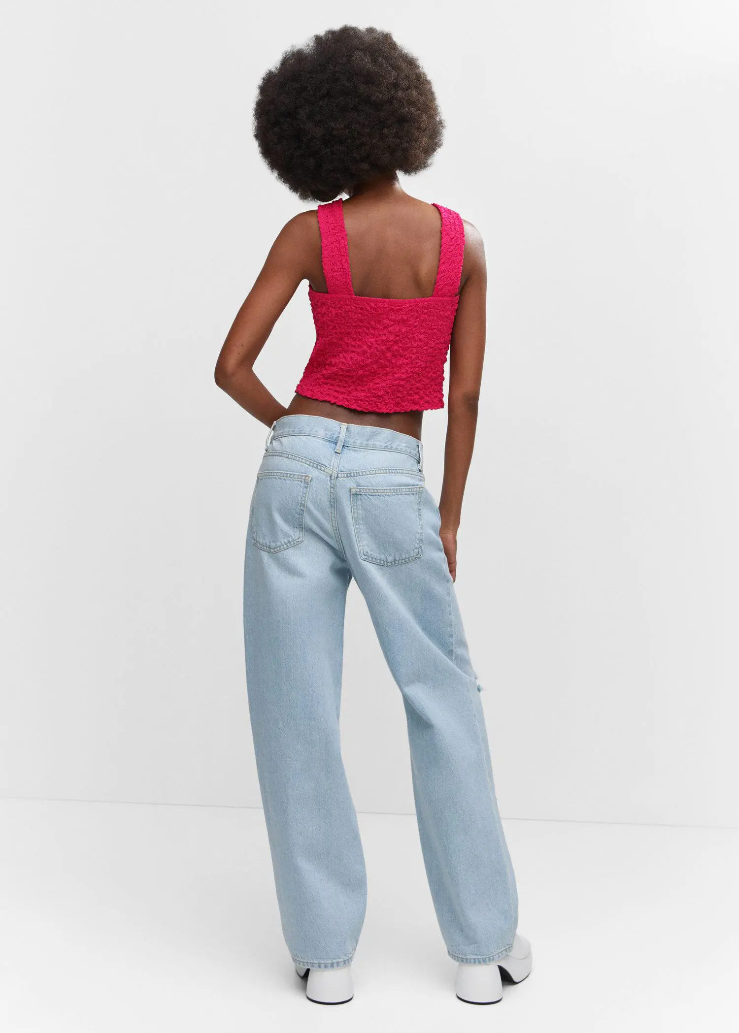 Mango Textured top with ring detail. a woman in a red top and light blue jeans. 
