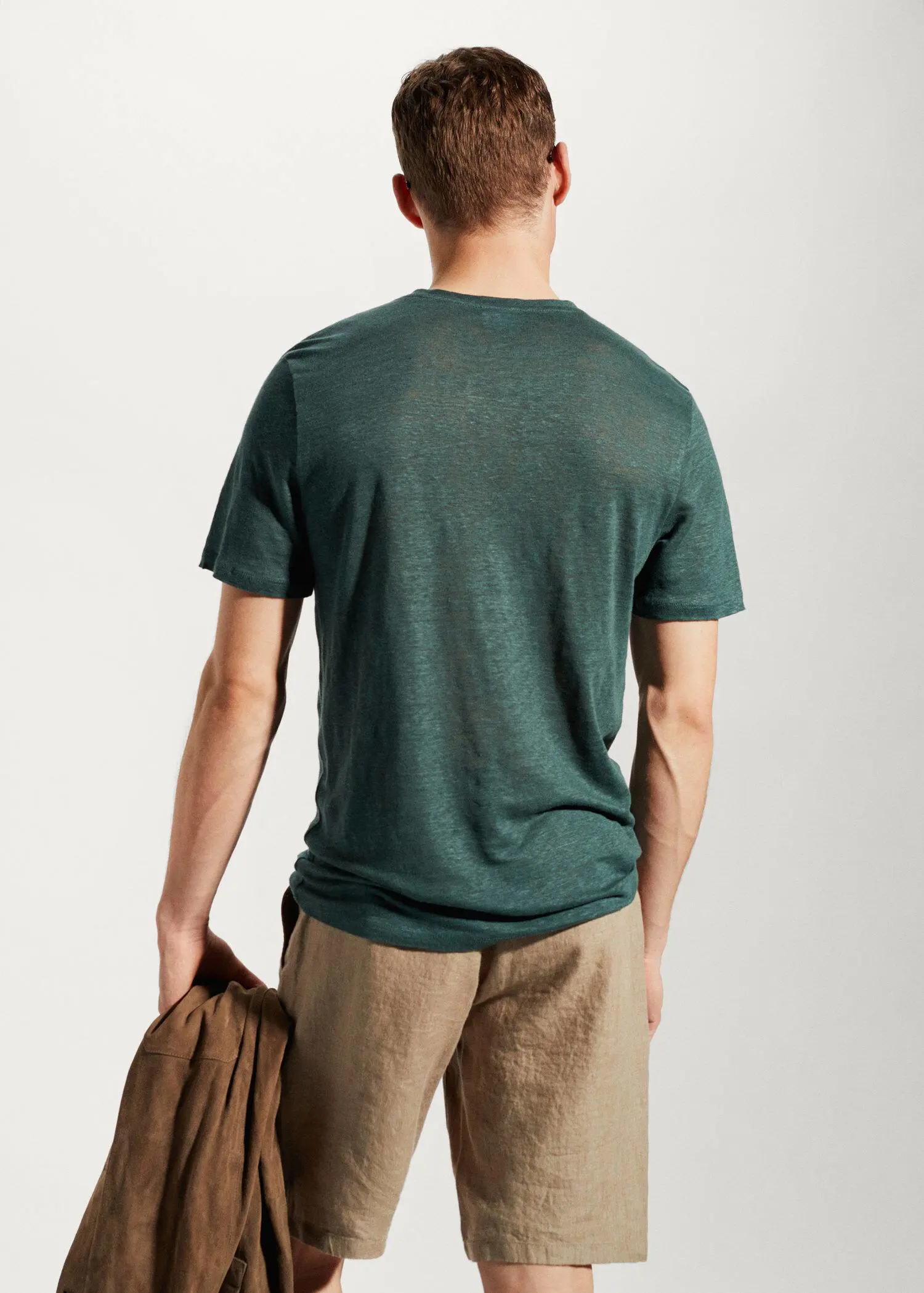 Mango 100% linen slim-fit t-shirt. a man in a green shirt holding a brown bag. 