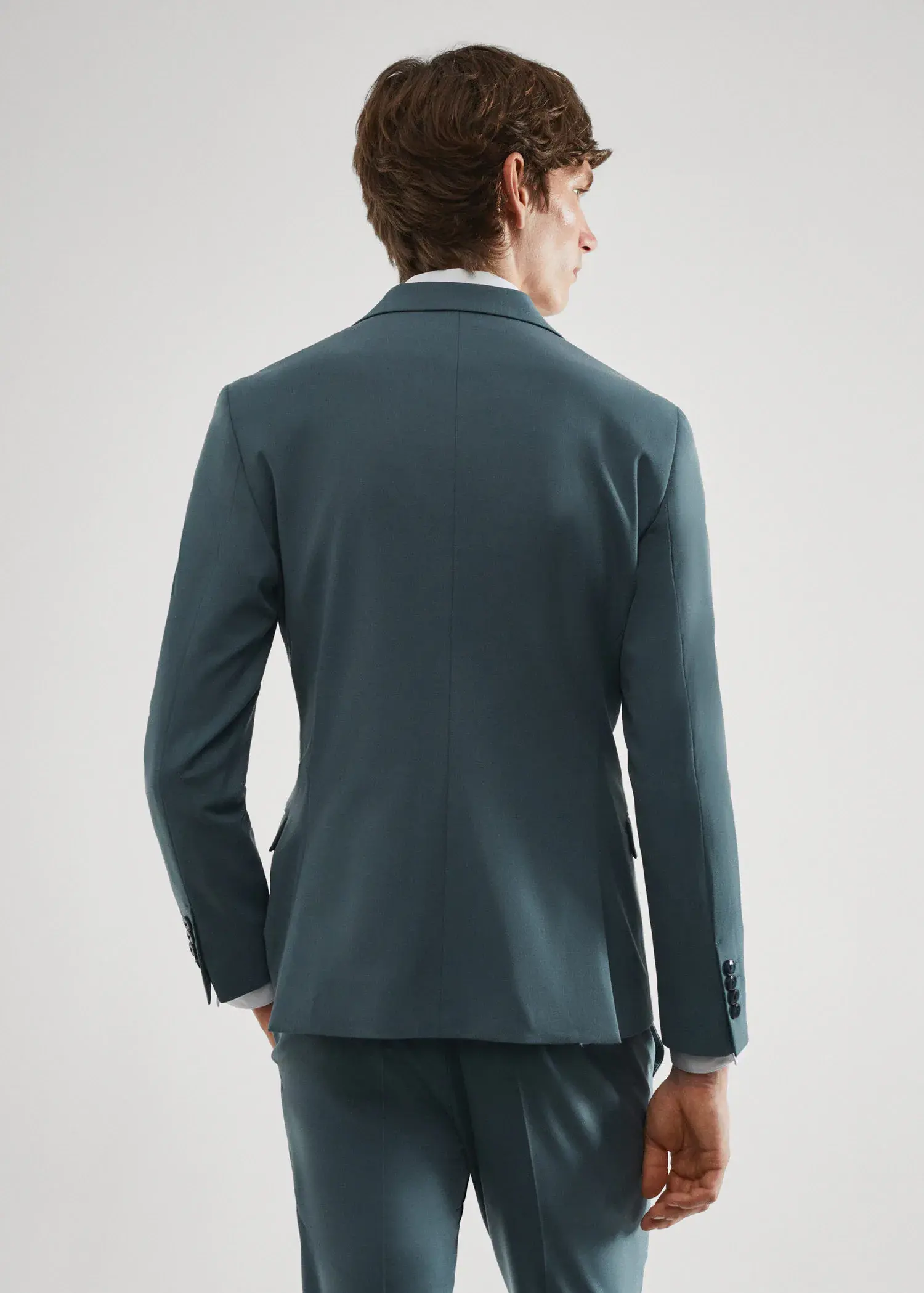 Mango Super slim-fit suit jacket in stretch fabric. a man wearing a suit standing in front of a white wall. 