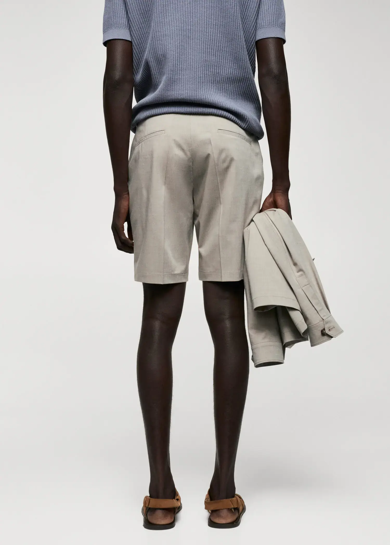 Mango Slim-fit bermuda shorts with adjustable waist. a man holding a jacket and wearing shorts. 