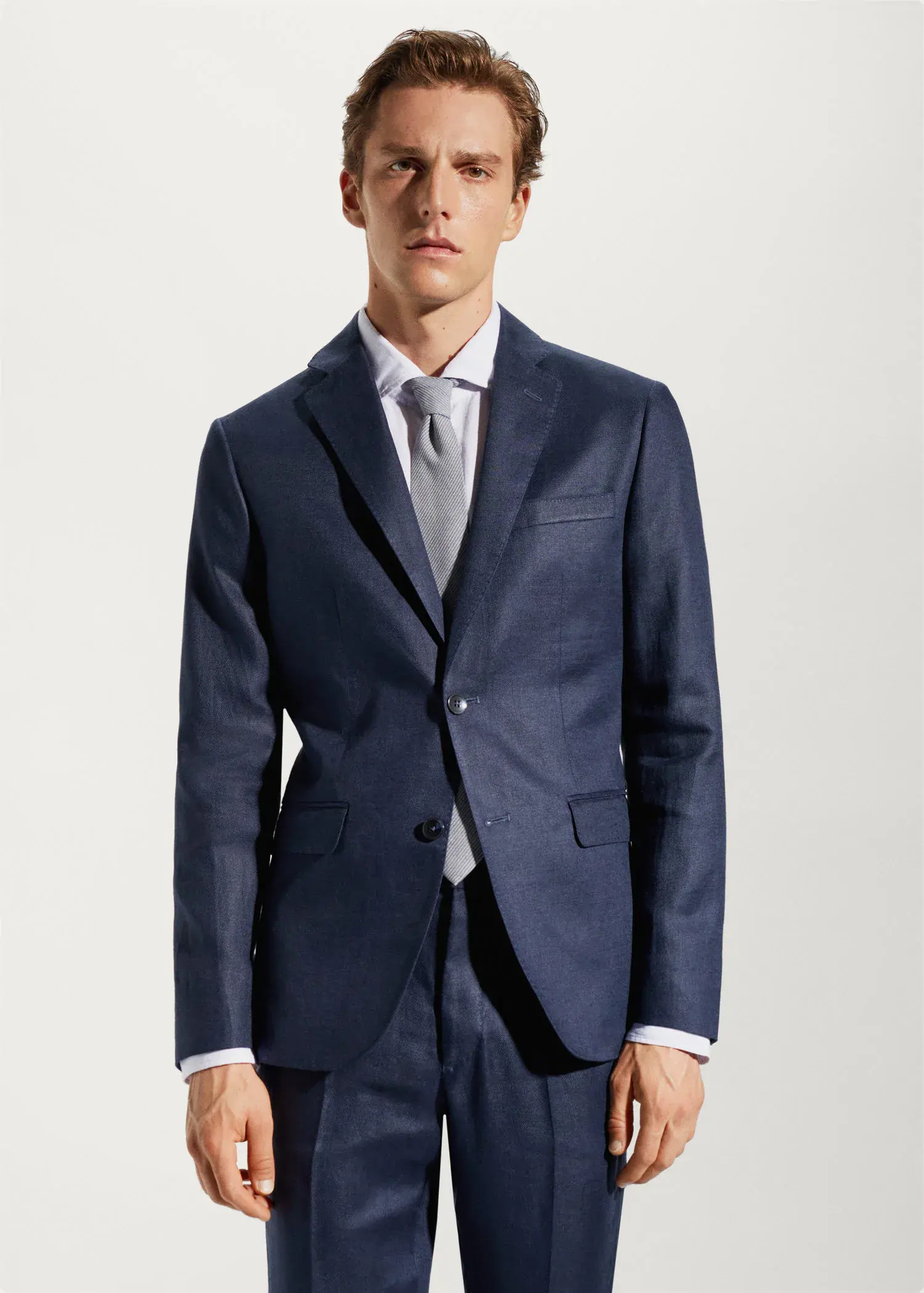 Mango 100% linen suit blazer. a man wearing a suit and tie standing in front of a wall. 