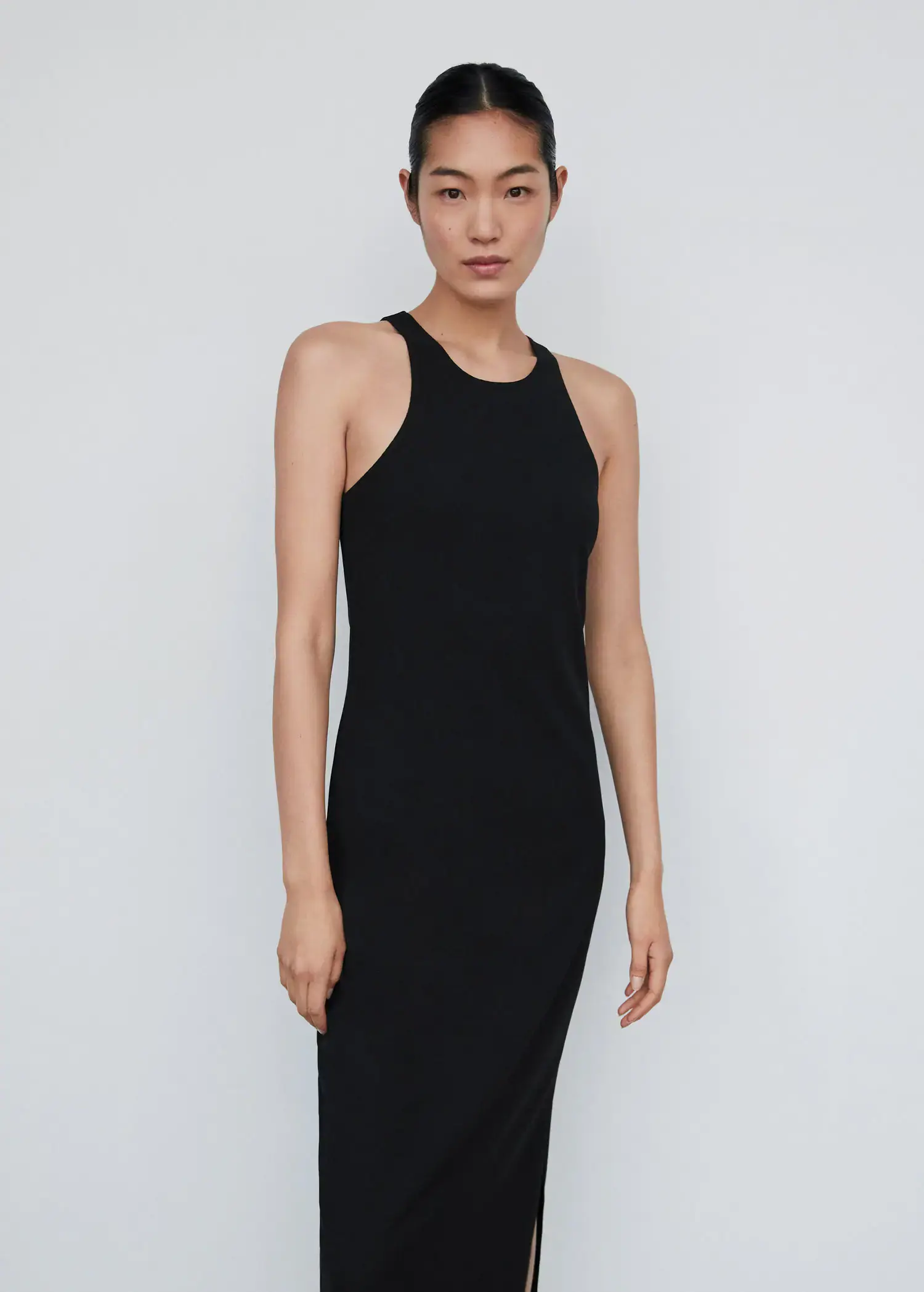 Mango Midi-dress with slit. a woman wearing a black dress standing in front of a white wall. 