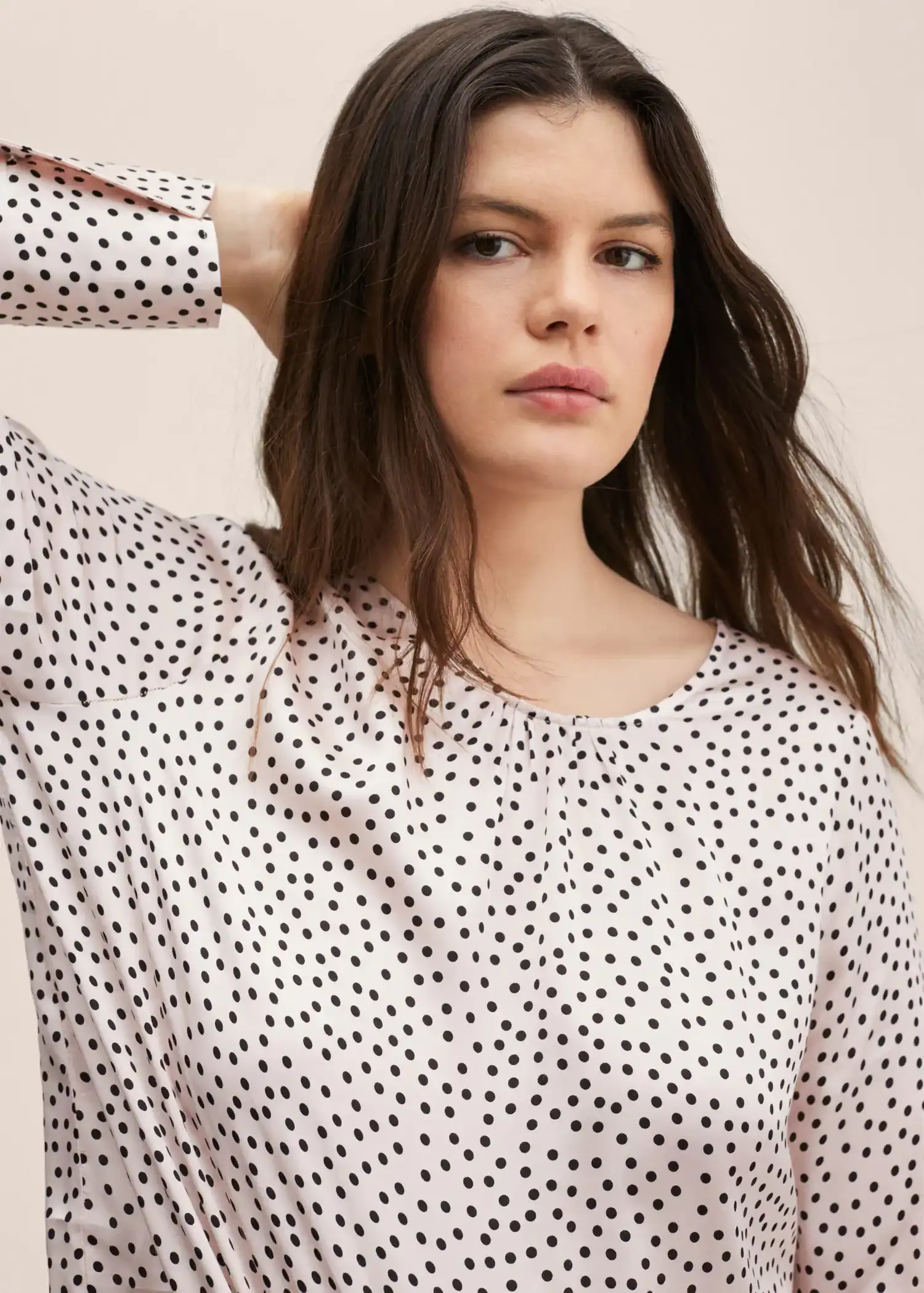 Mango Polka-dot blouse. a woman in a polka dot shirt holding her hair. 