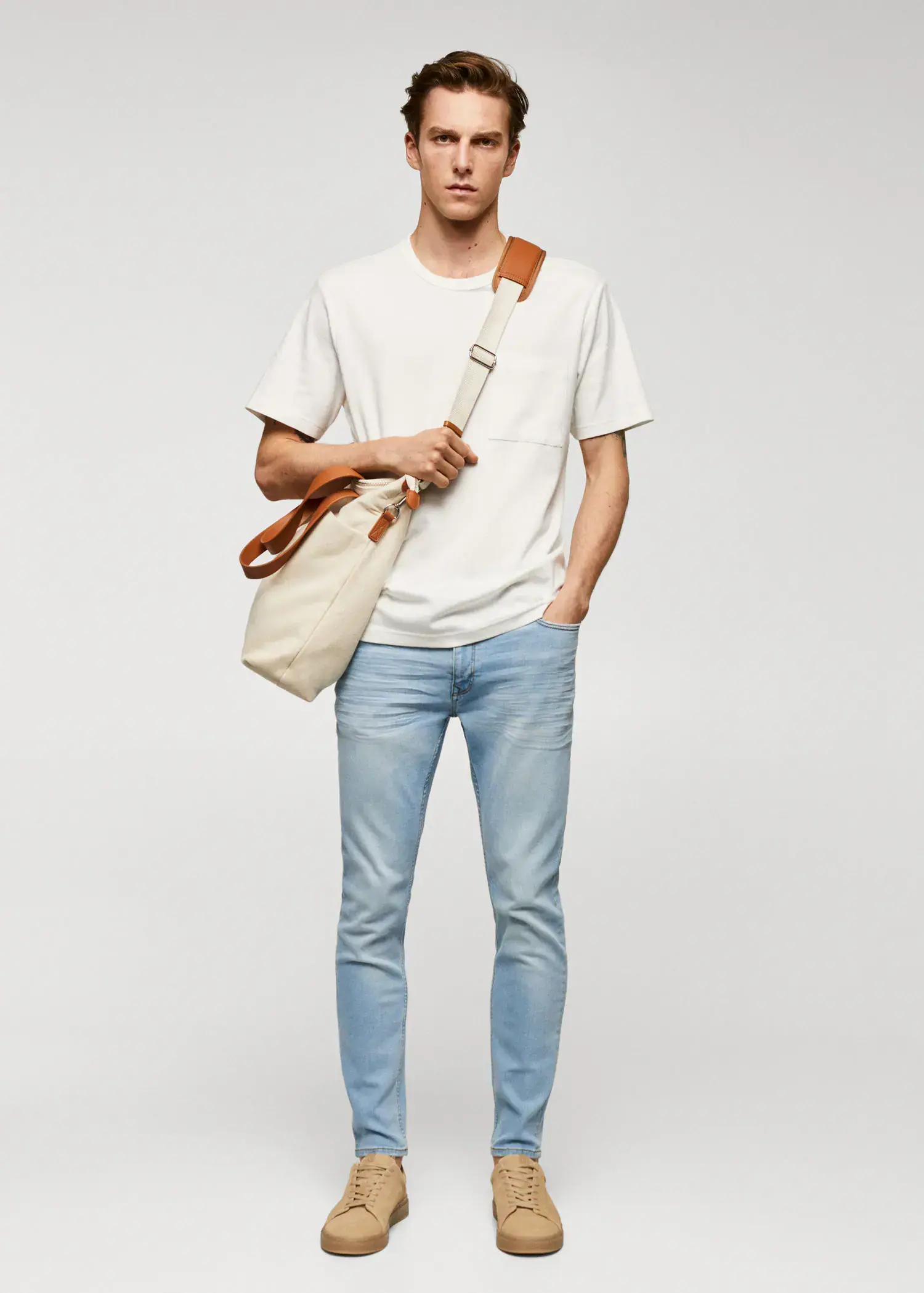 Mango Jude skinny-fit jeans. a man holding a bag while standing in a room. 