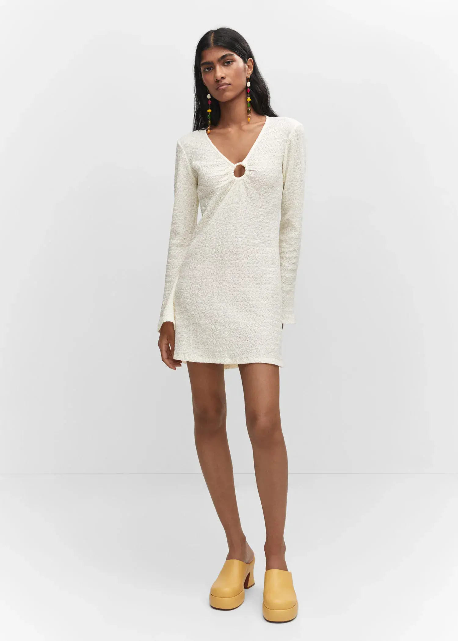 Mango Textured dress with hoop detail. a woman in a white dress standing in a room. 