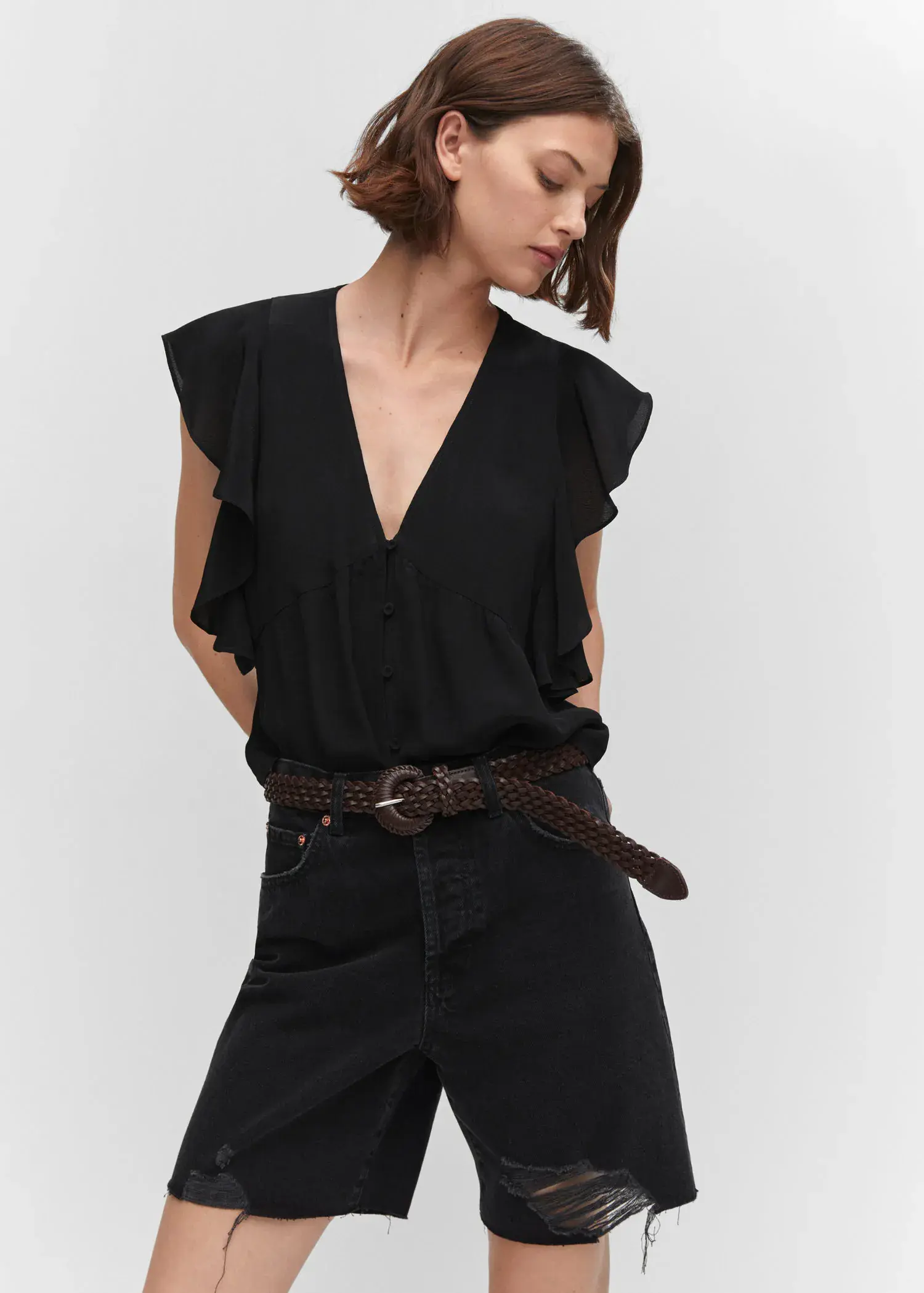 Mango Ruffled blouse. a woman wearing a black top and a brown belt. 