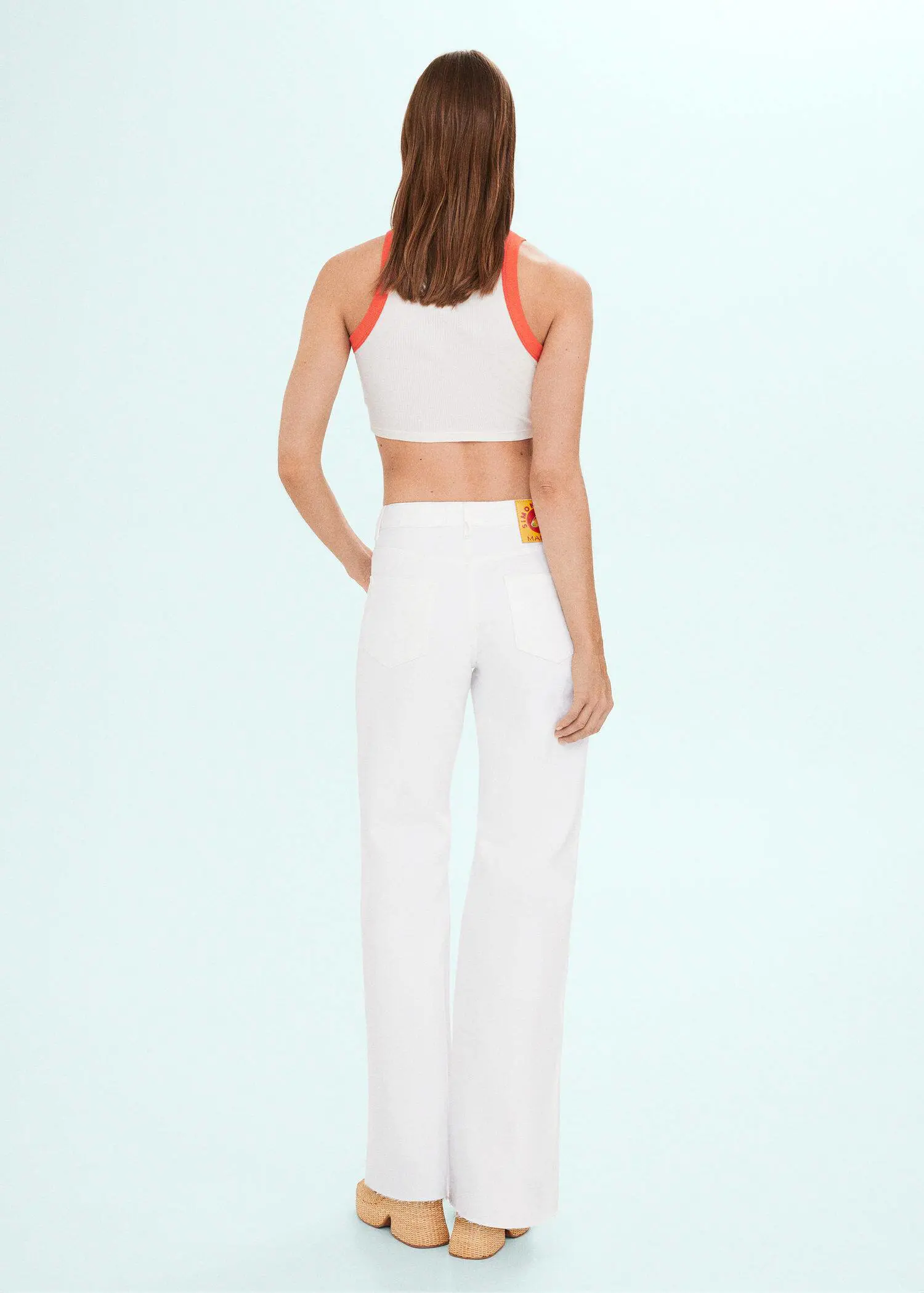 Mango High-rise wideleg jeans . a woman wearing white pants and an orange and white top. 