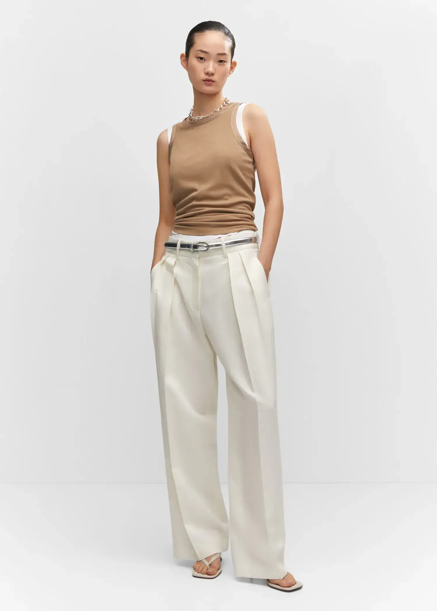Mango Wideleg pleated trousers. a woman in a tan tank top and white pants. 