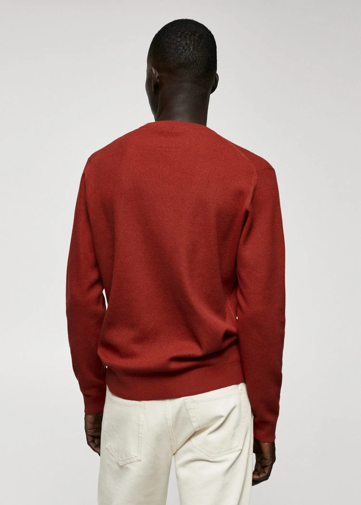 Mango Structured cotton sweater. a man wearing a red sweater standing in front of a wall. 