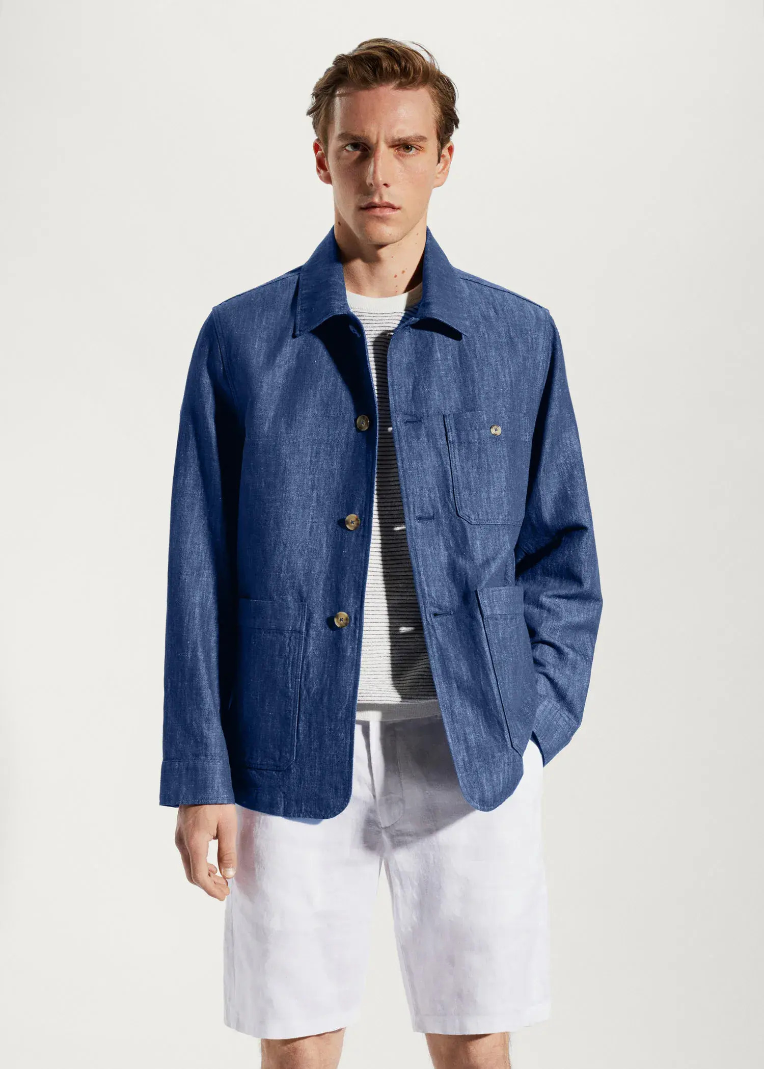 Mango Cotton-linen jacket with pockets. a man wearing a blue jacket standing in front of a wall. 