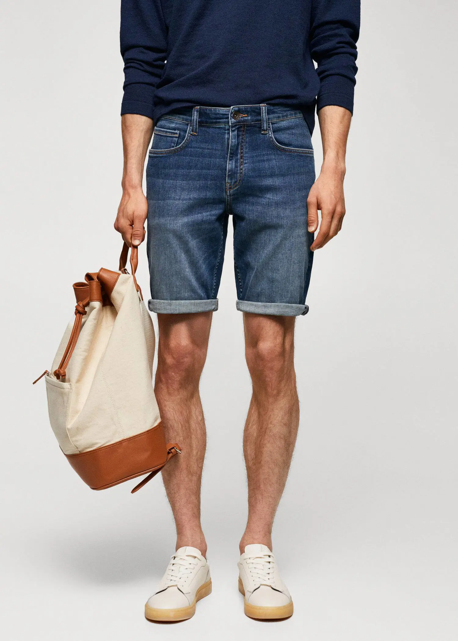 Mango Slim-fit denim bermuda shorts. a man holding a bag while wearing shorts. 
