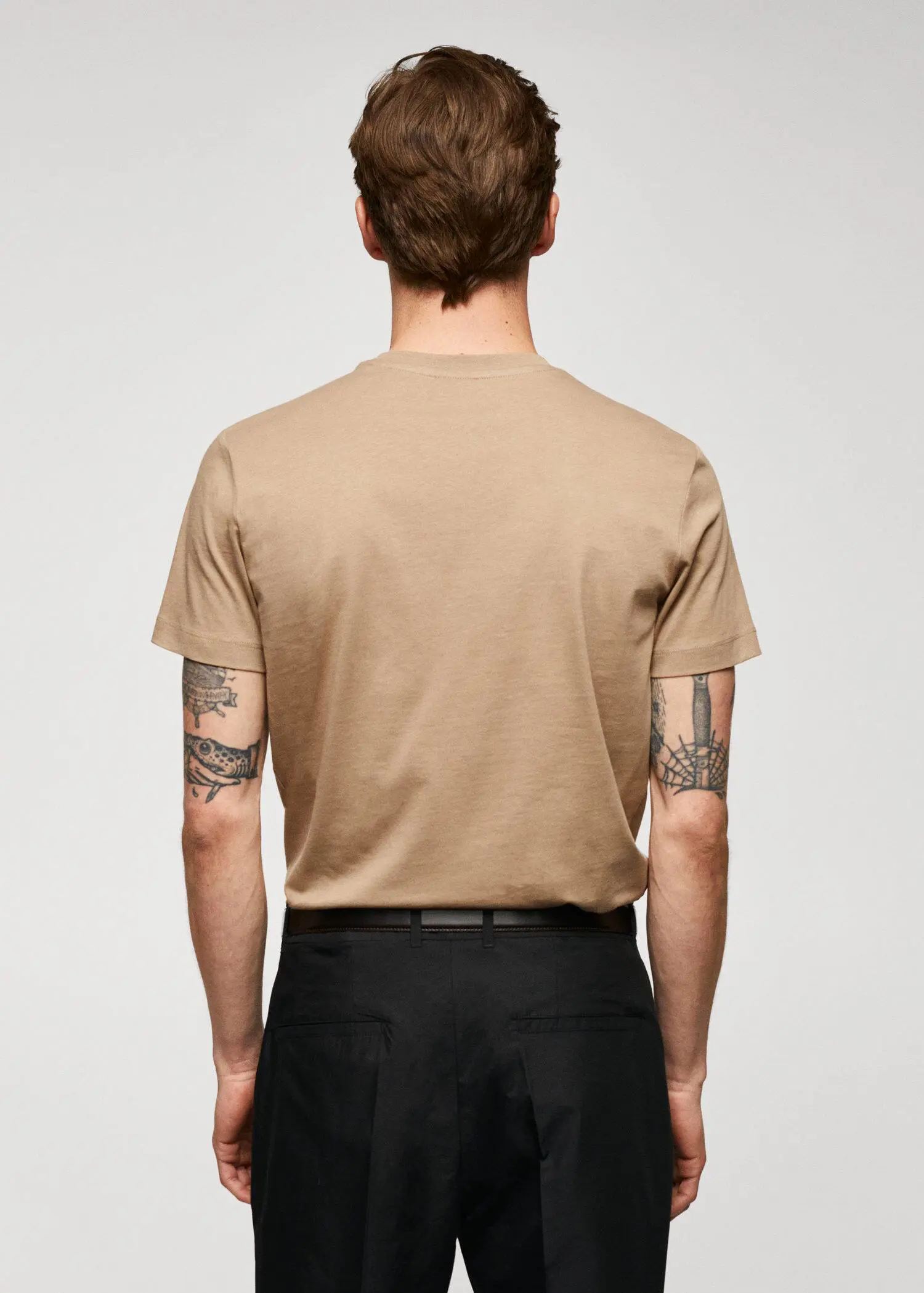 Mango Basic cotton stretch T-shirt. a man wearing a tan t-shirt and black pants. 