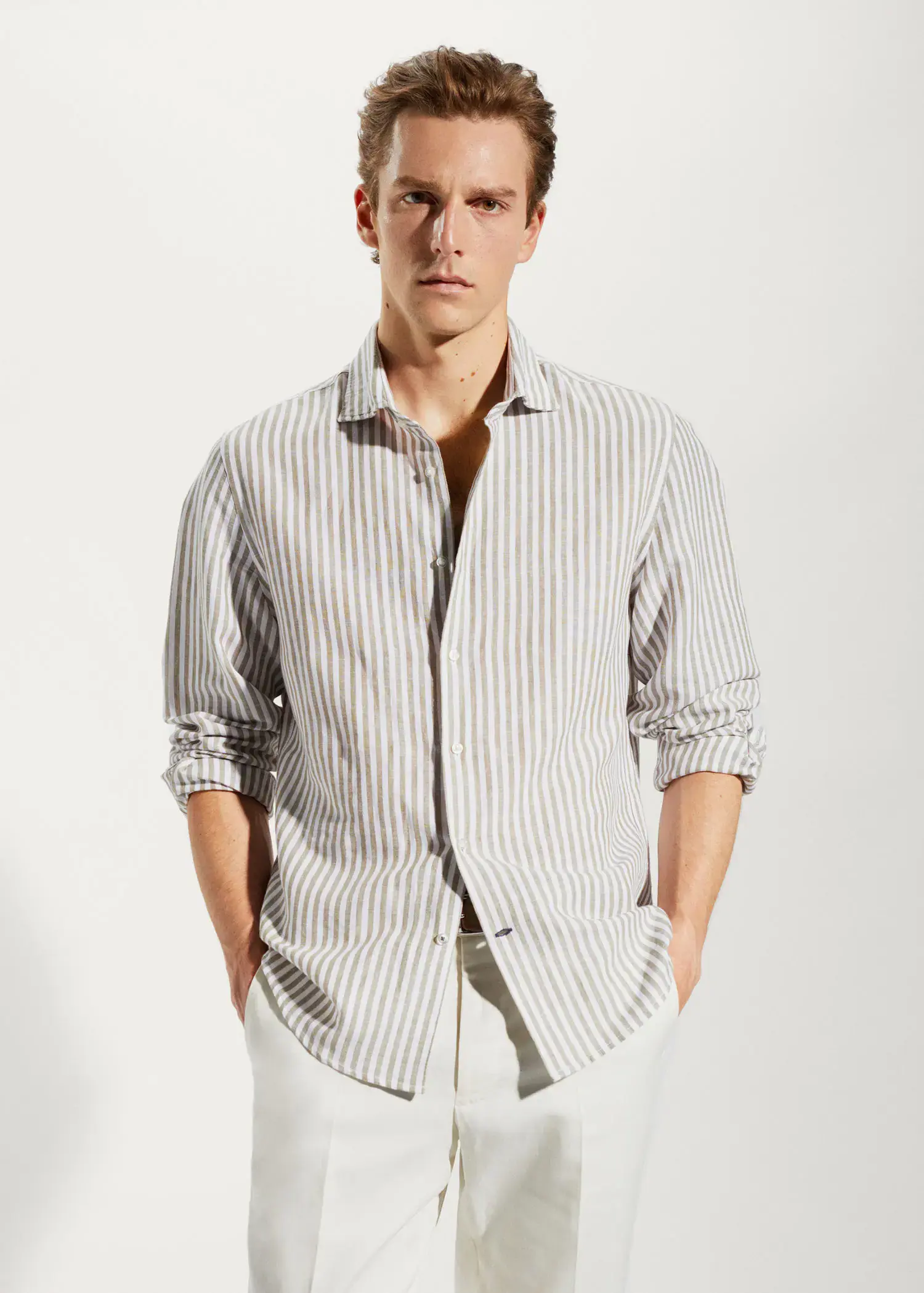 Mango Slim fit striped linen shirt. a man in a striped shirt is standing with his hands in his pockets 