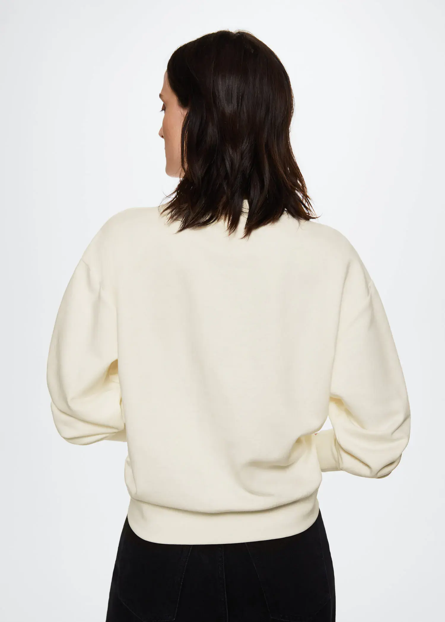Mango Embroidered message sweatshirt. a woman wearing a white sweatshirt standing in front of a wall. 