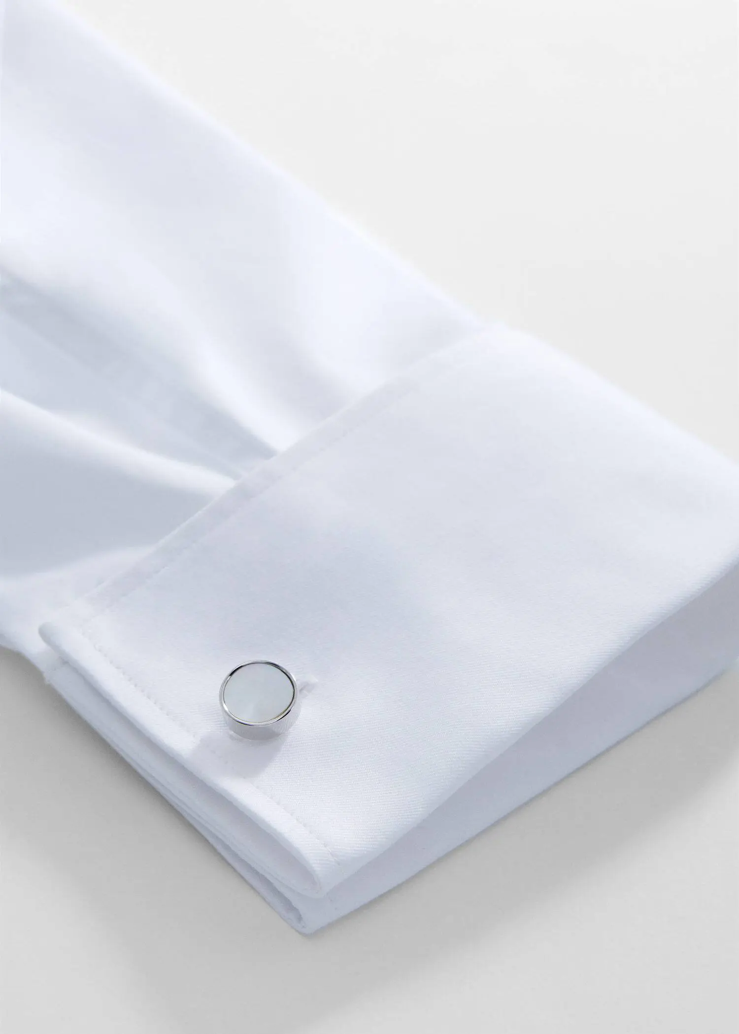 Mango Round mother-of-pearl cufflinks. a close-up of a white shirt and a silver ring. 