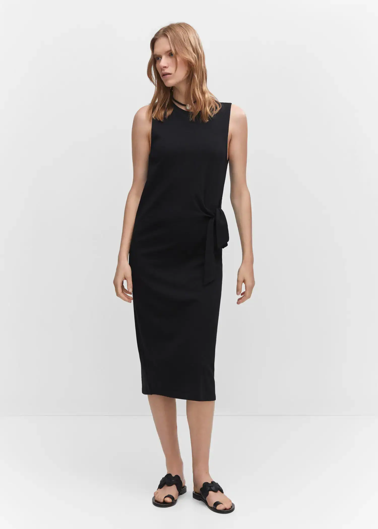 Mango Bow cut-out detail dress. a woman wearing a black dress standing in a room. 