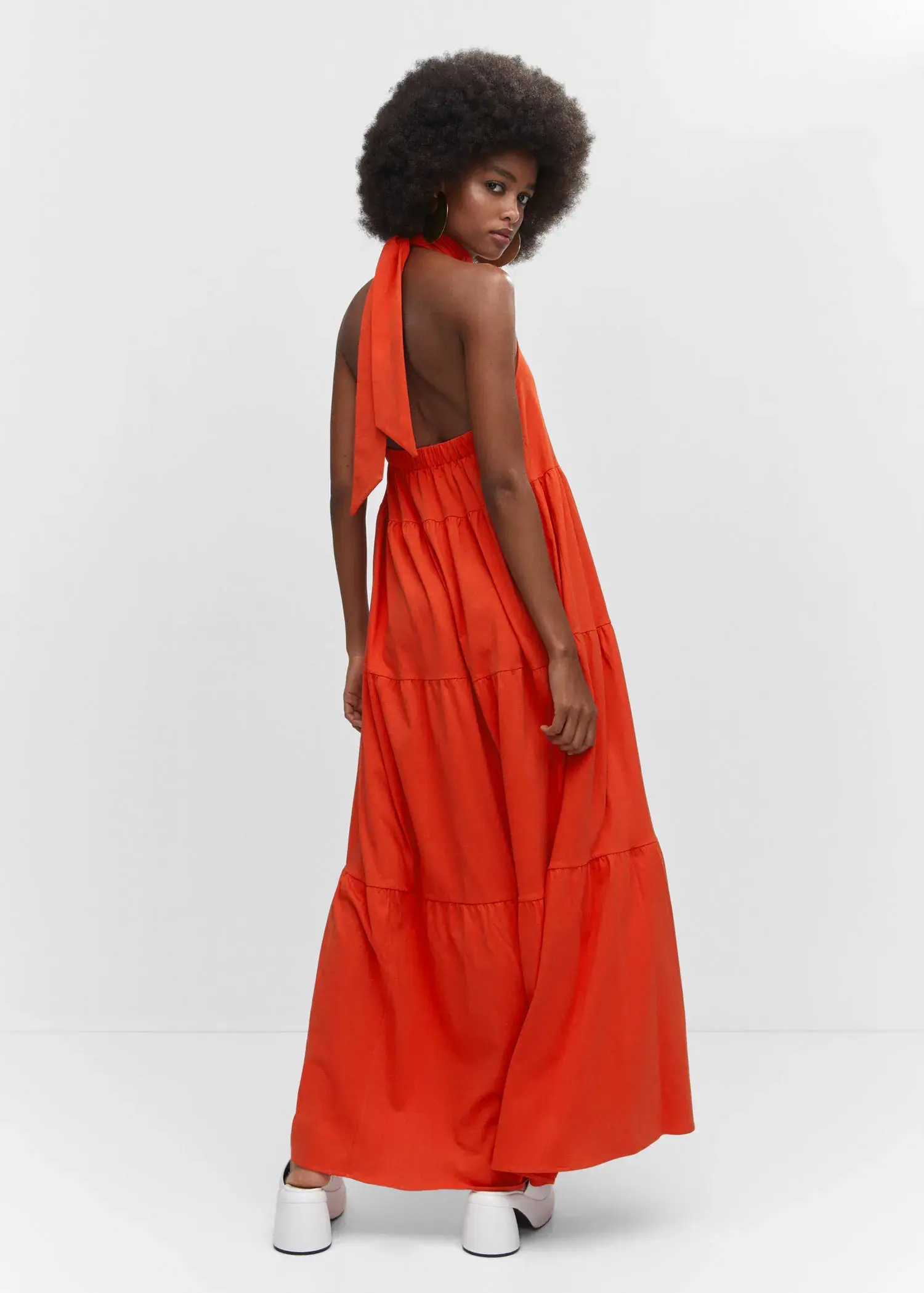 Mango Halter-neck open-back dress. a woman in an orange dress standing in front of a white wall. 