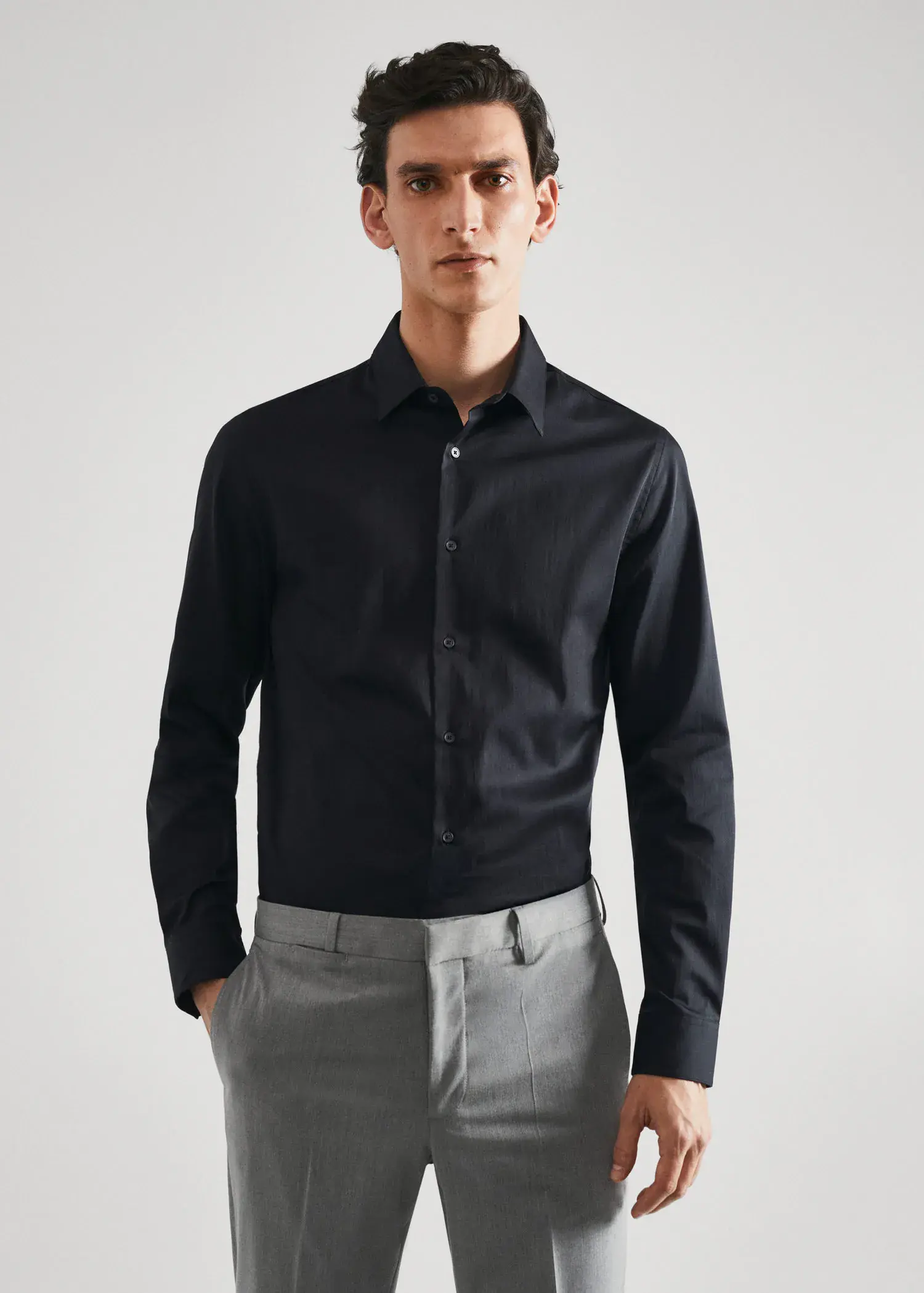 Mango Super slim-fit poplin suit shirt. a man wearing a black shirt and gray pants. 
