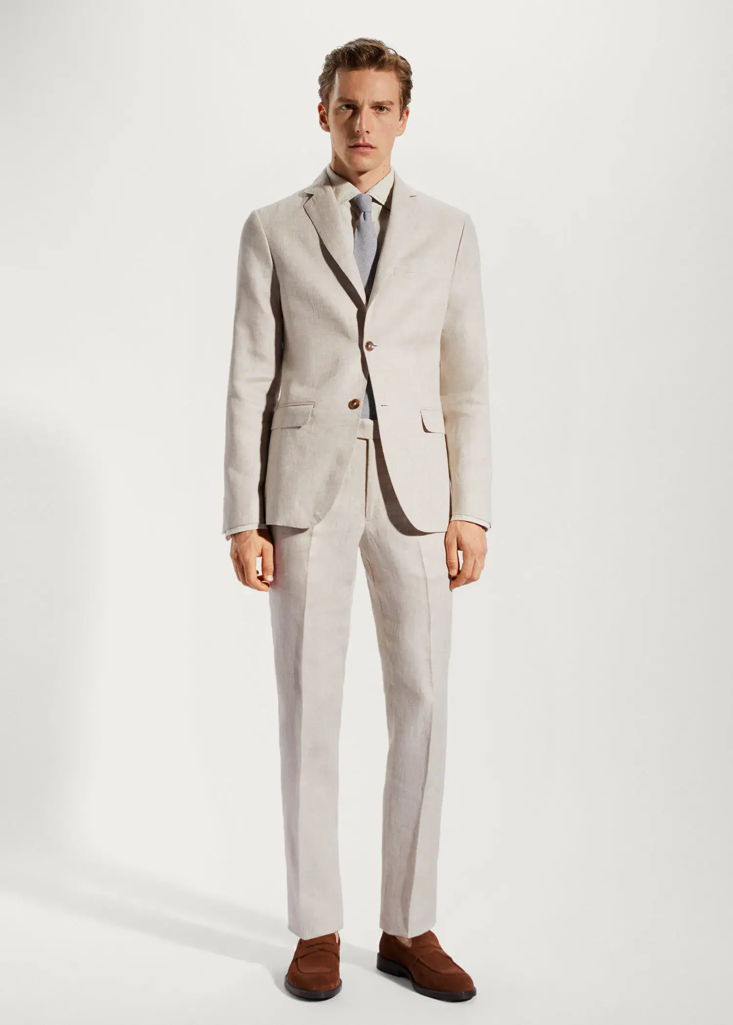 Mango 100% linen suit blazer. a man wearing a suit and tie standing in front of a white wall. 