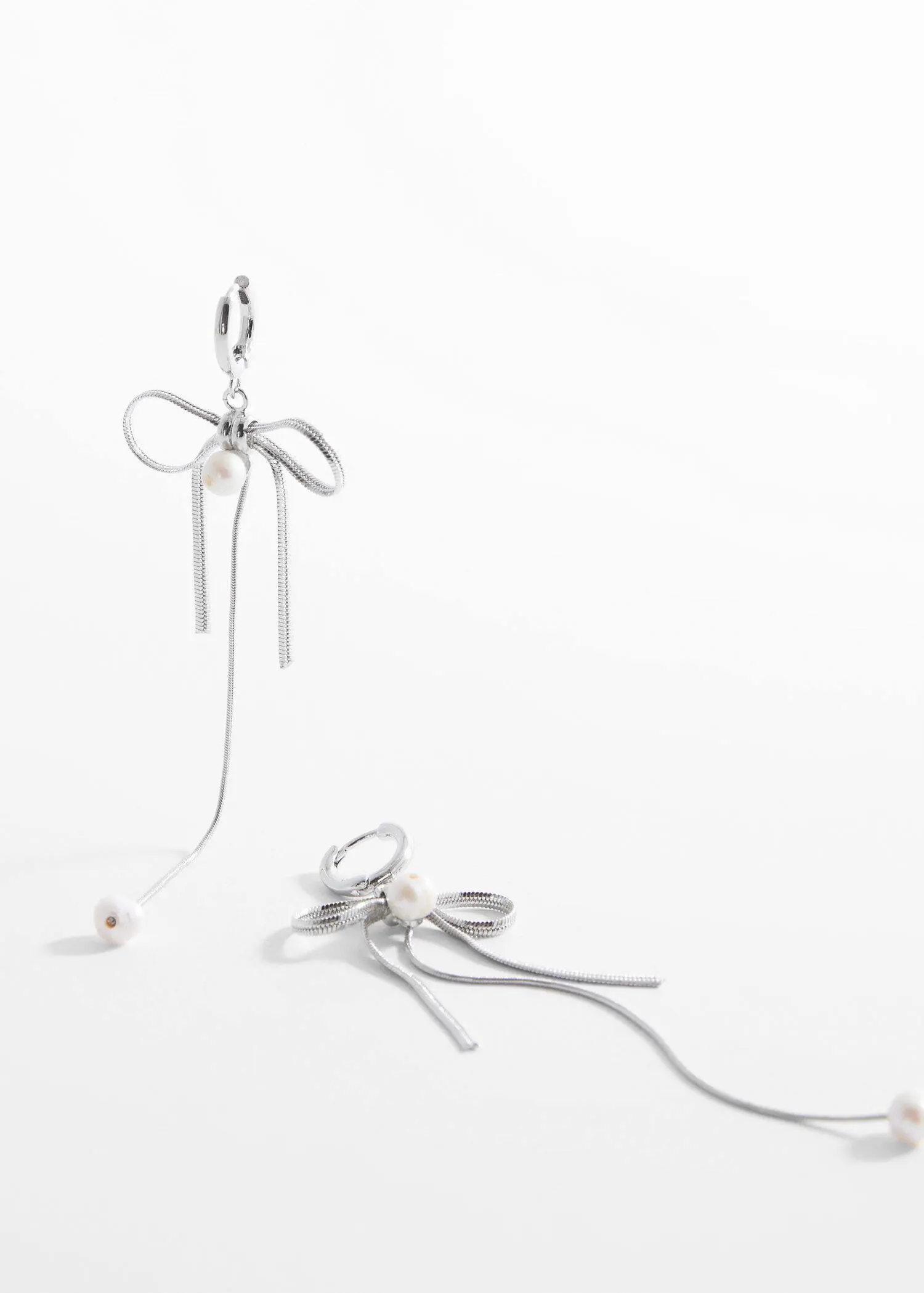 Mango Pearl bow earings. a pair of silver earrings with a bow hanging off of them. 