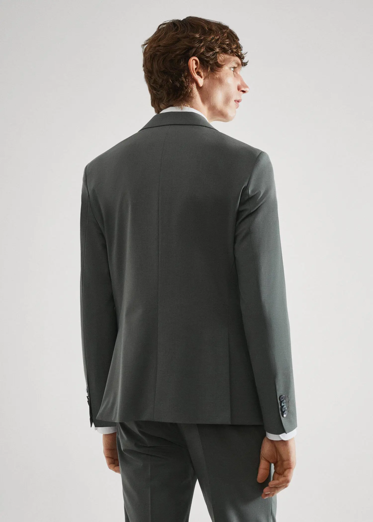 Mango Slim-fit wool suit jacket. a man wearing a suit standing in front of a white wall. 