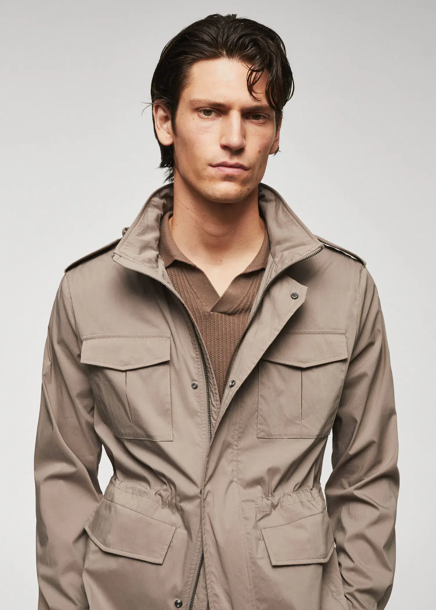 Mango Lightweight saharian jacket with pockets. a man in a tan jacket is posing for a picture. 