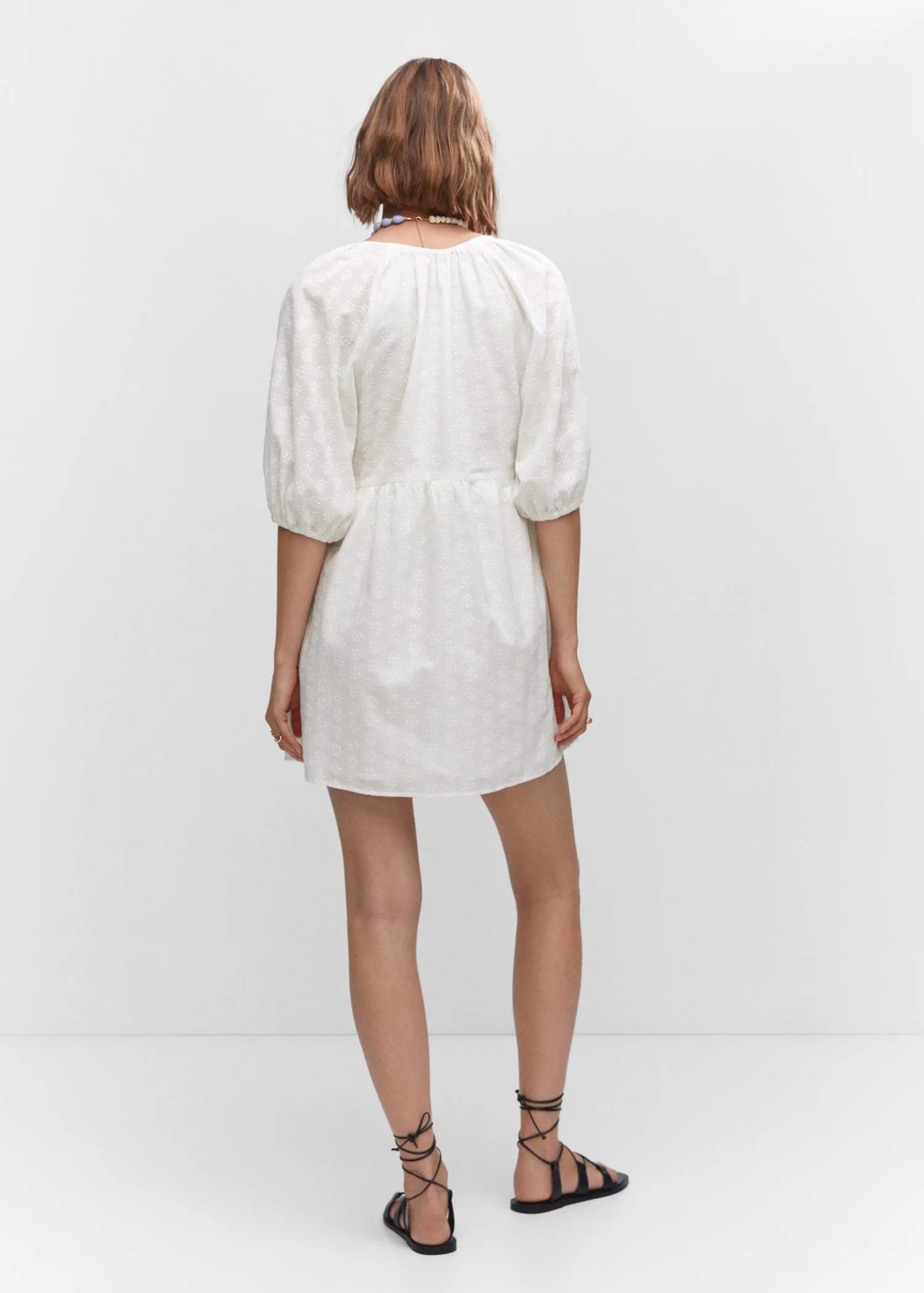 Mango Puff-sleeved embroidered dress. a person wearing a white dress standing in a room. 