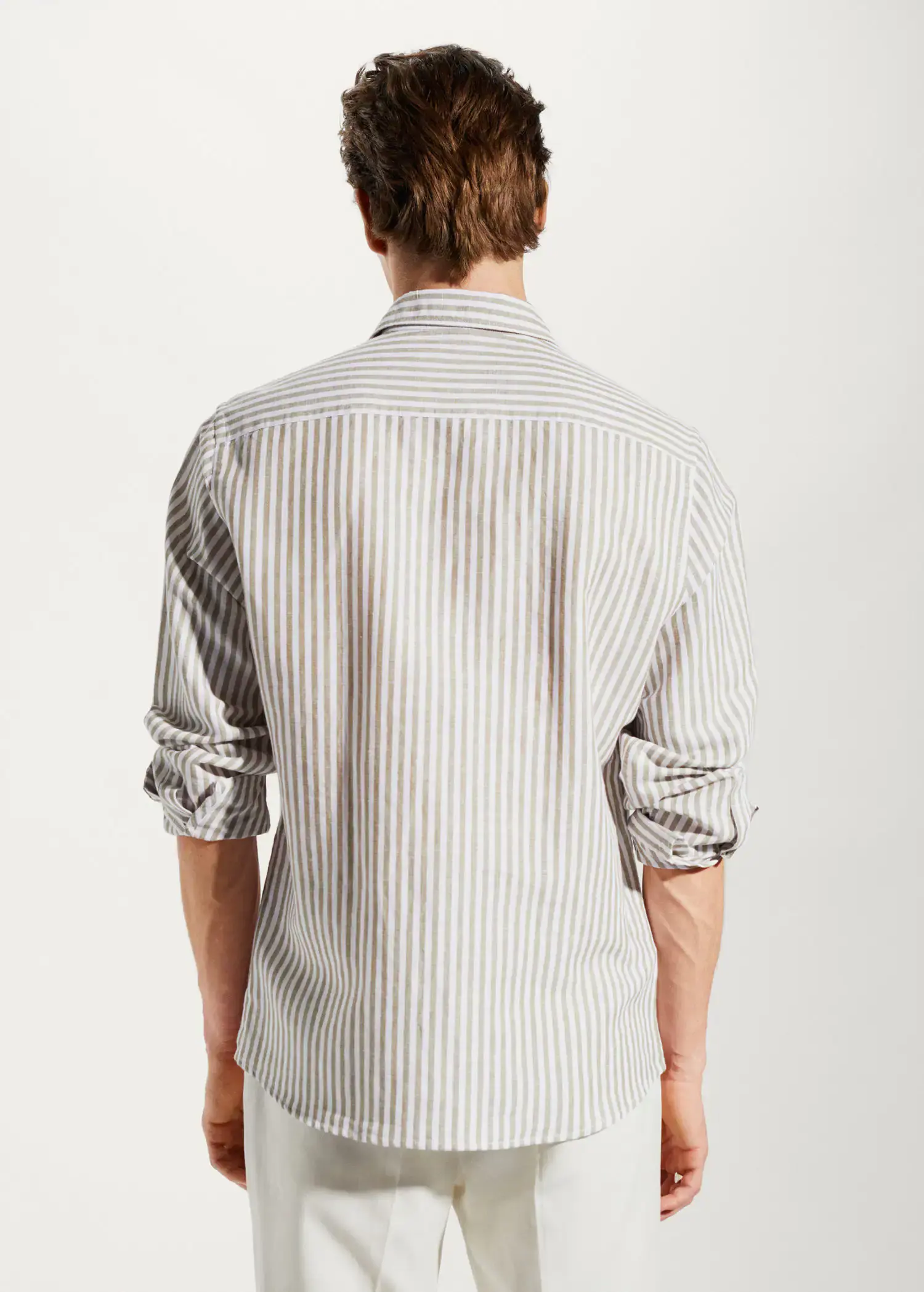 Mango Slim fit striped linen shirt. a man wearing a striped shirt is standing up. 