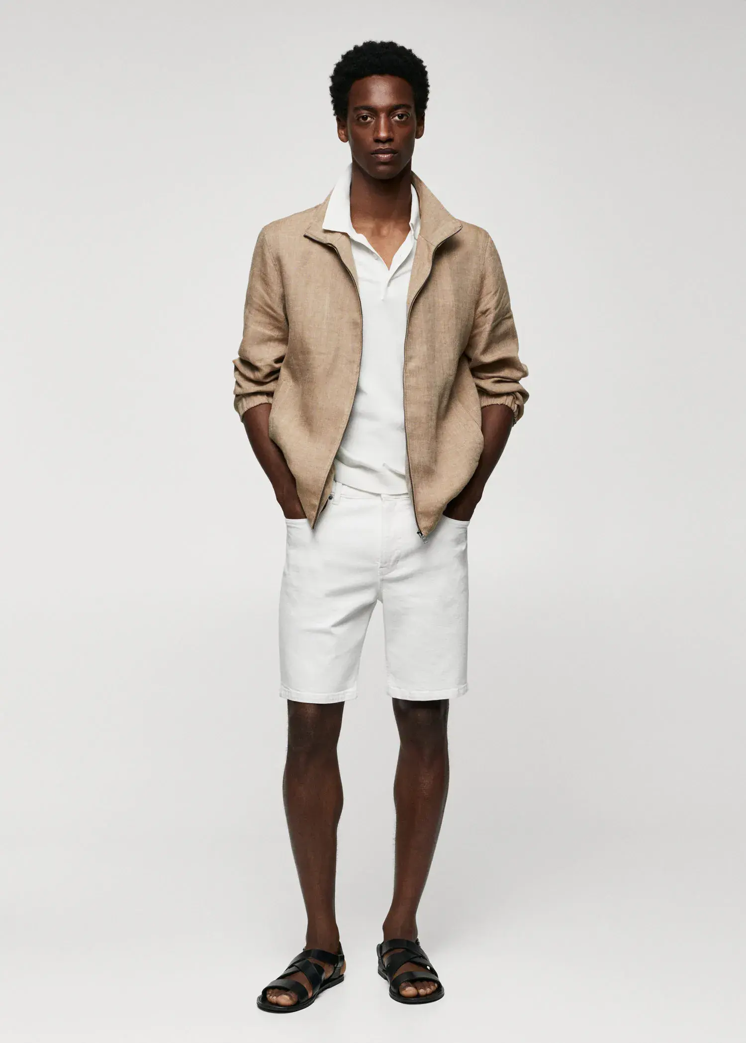Mango Regular-fit denim bermuda shorts. a man wearing a tan jacket and white shorts. 