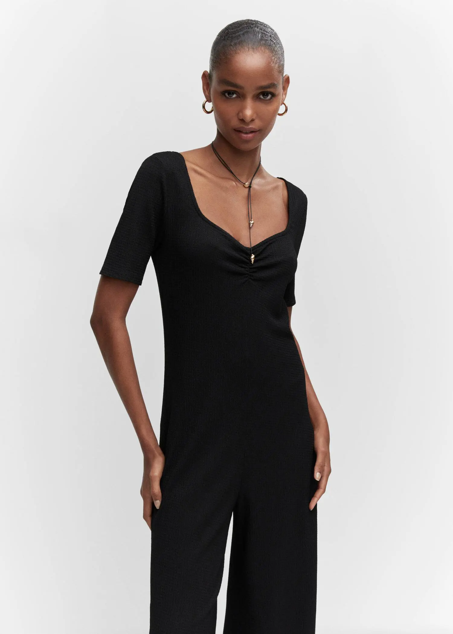 Mango Ruched long jumpsuit. a woman in a black outfit posing for a picture. 