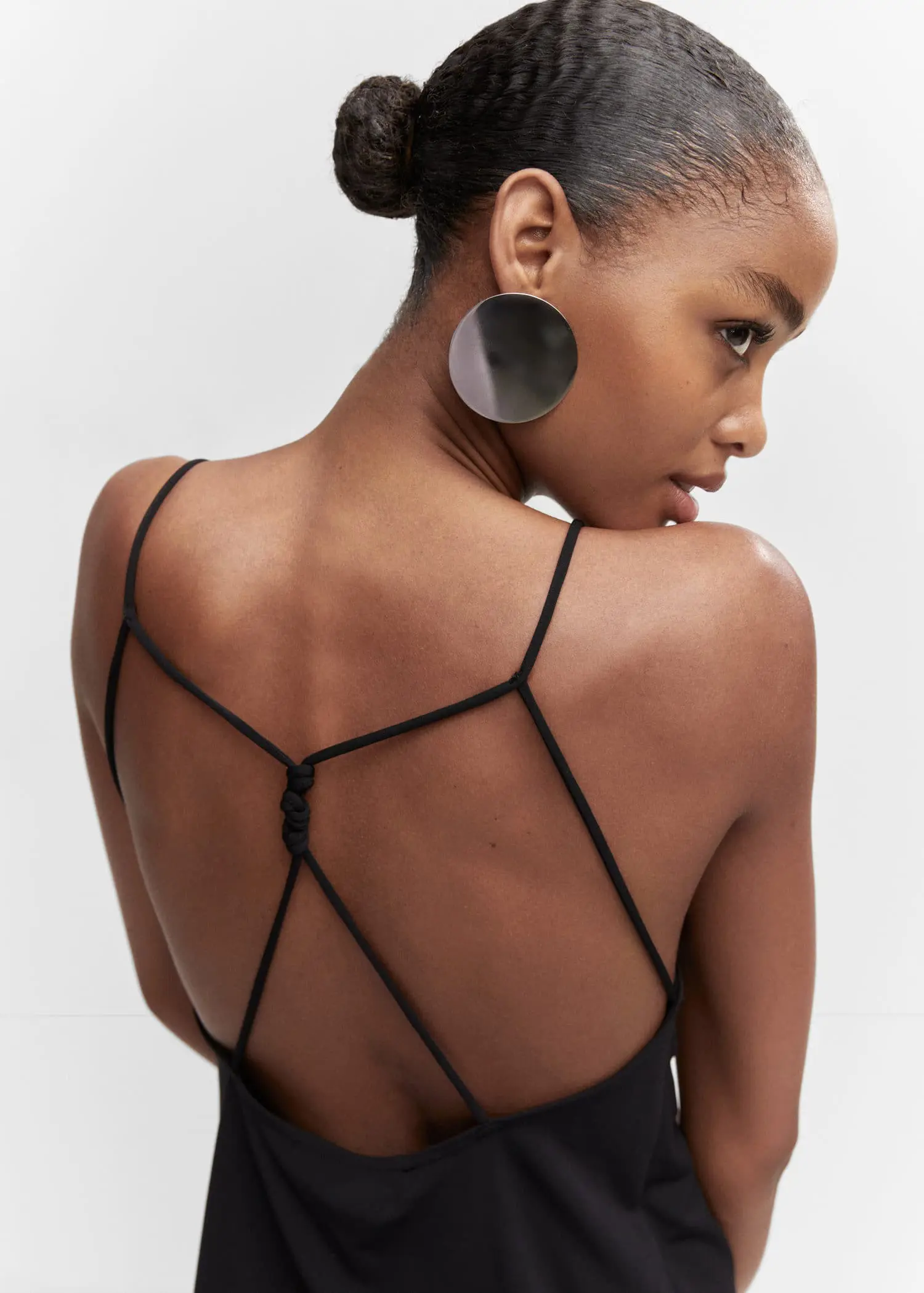 Mango Wrap back top. a young woman wearing a black dress and a pair of earrings. 
